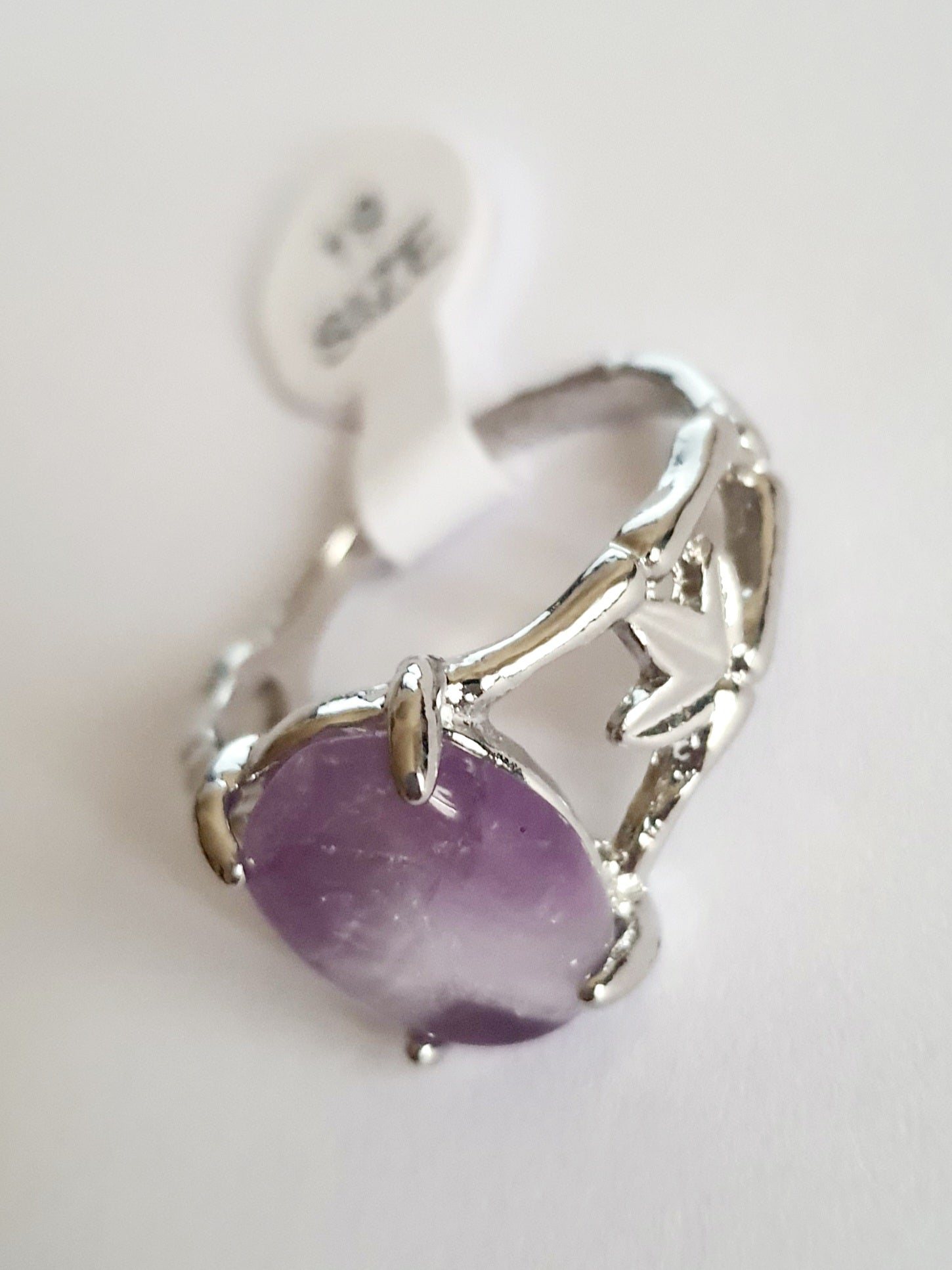 Srebrny pierścionek z fioletowym kamieniem przypominającym ametyst, w romantycznym stylu. Stal chirurgiczna, delikatne metalowe zdobienia przypominające gałązki. Rozmiar 19 mm. Rouge Bizu.