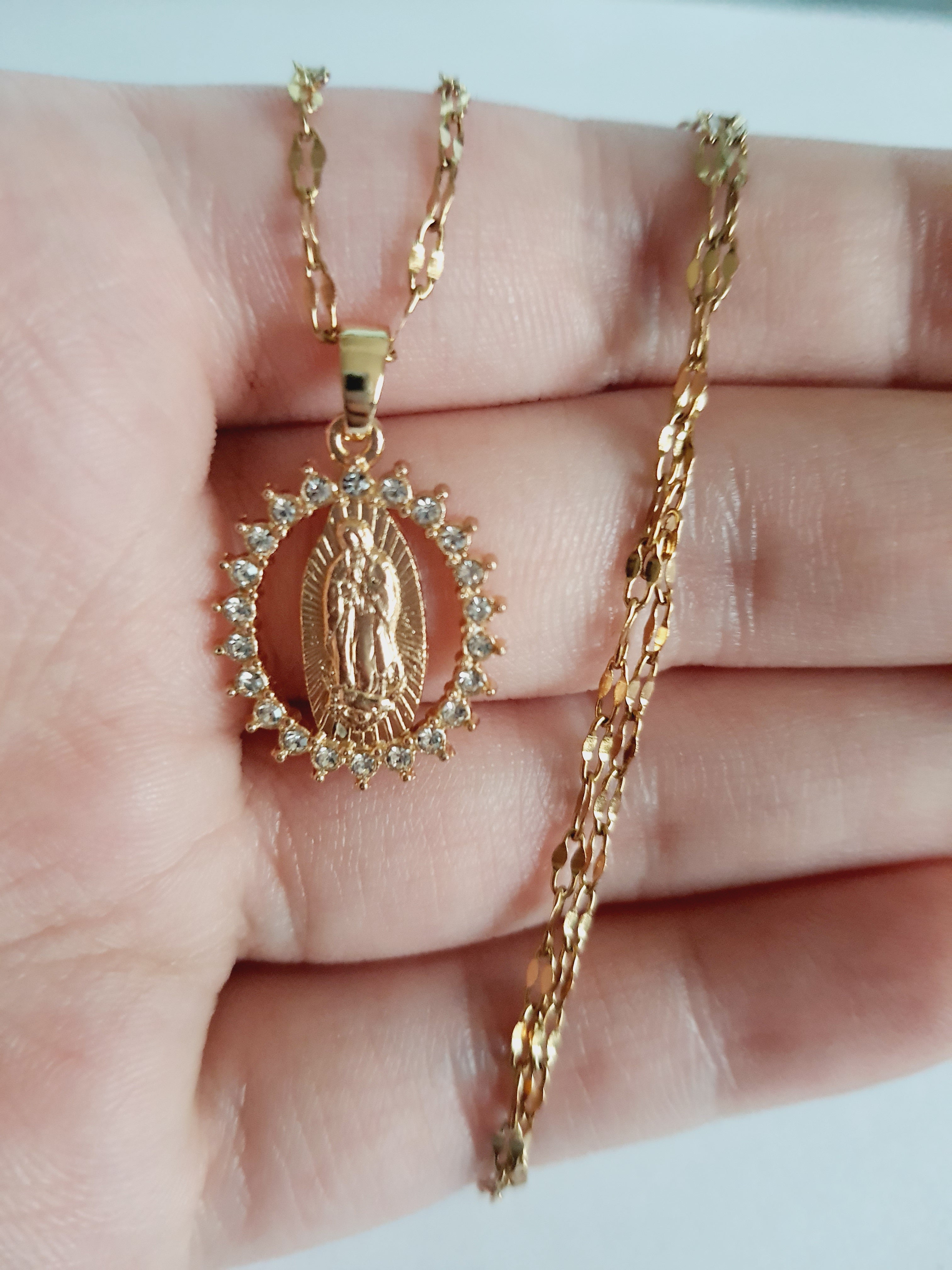 Złoty łańcuszek o długości 40–46 cm z wisiorkiem Matki Boskiej otoczonym cyrkoniami. Styl sakralny, elegancki. Stal nierdzewna, Rouge Bizu.