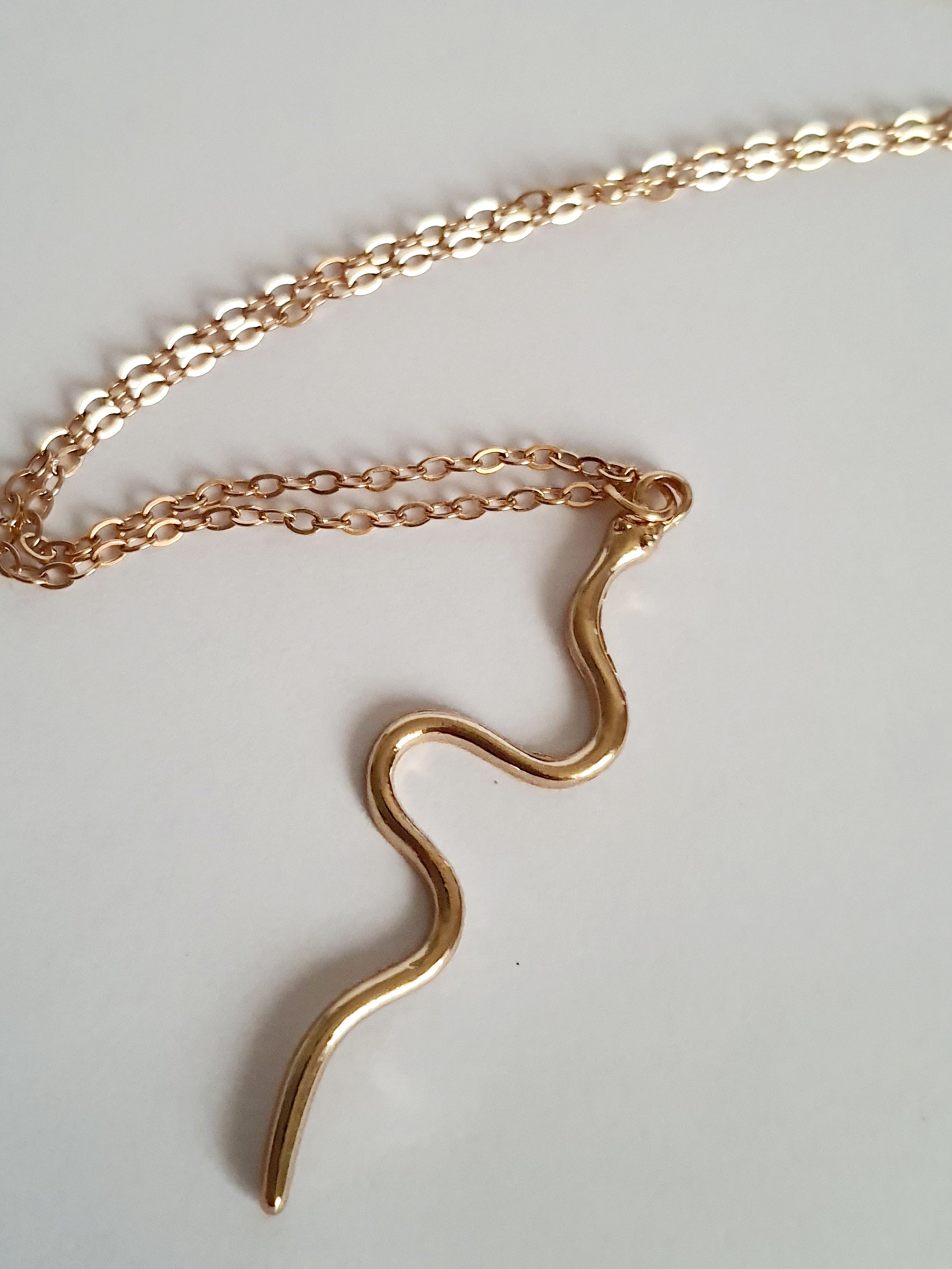 Złoty łańcuszek z falistą zawieszką, w kształcie węża, stal nierdzewna, długość regulowana 46–53 cm. Rouge Bizu.