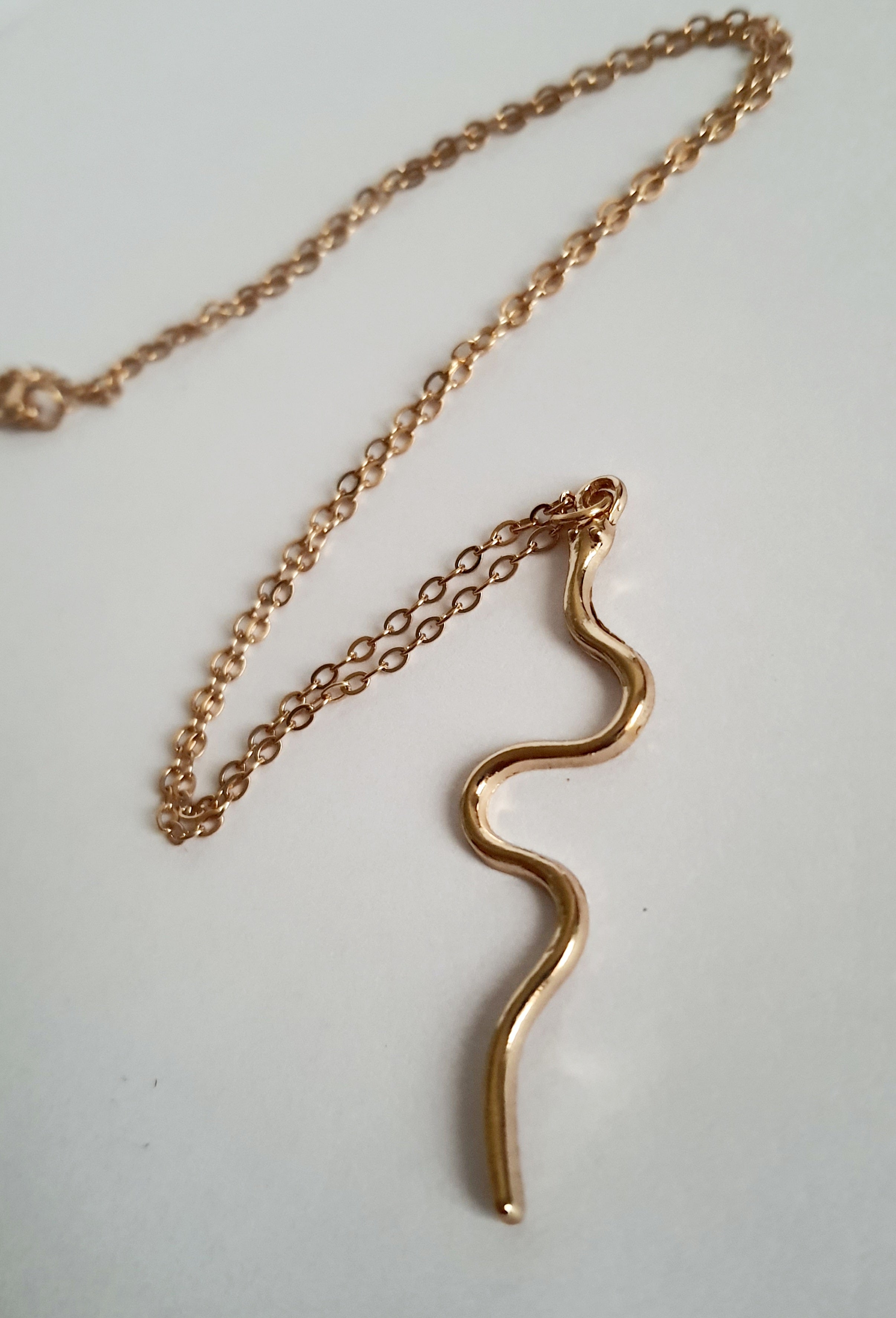 Złoty łańcuszek z falistą zawieszką, w kształcie węża, stal nierdzewna, długość regulowana 46–53 cm. Rouge Bizu.