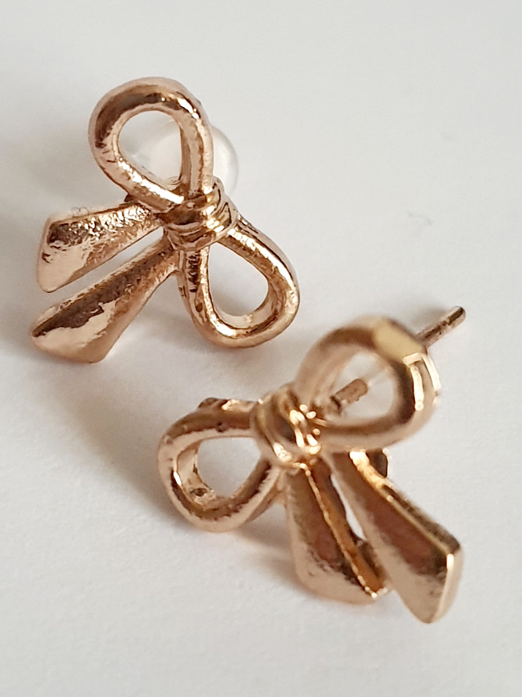 Złote kolczyki kokardki wkrętki, stal nierdzewna, długość 1,5 cm, subtelny romantyczny styl. Rouge Bizu.