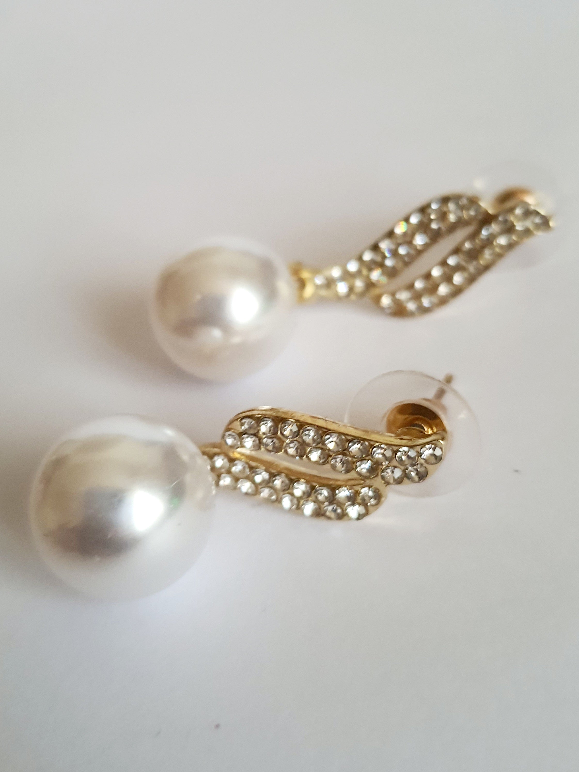 Kolczyki złote ze stali nierdzewnej o długości 4 cm, z dużą białą perłą i złotą falą wysadzaną cyrkoniami, elegancja i blask, Rouge Bizu.