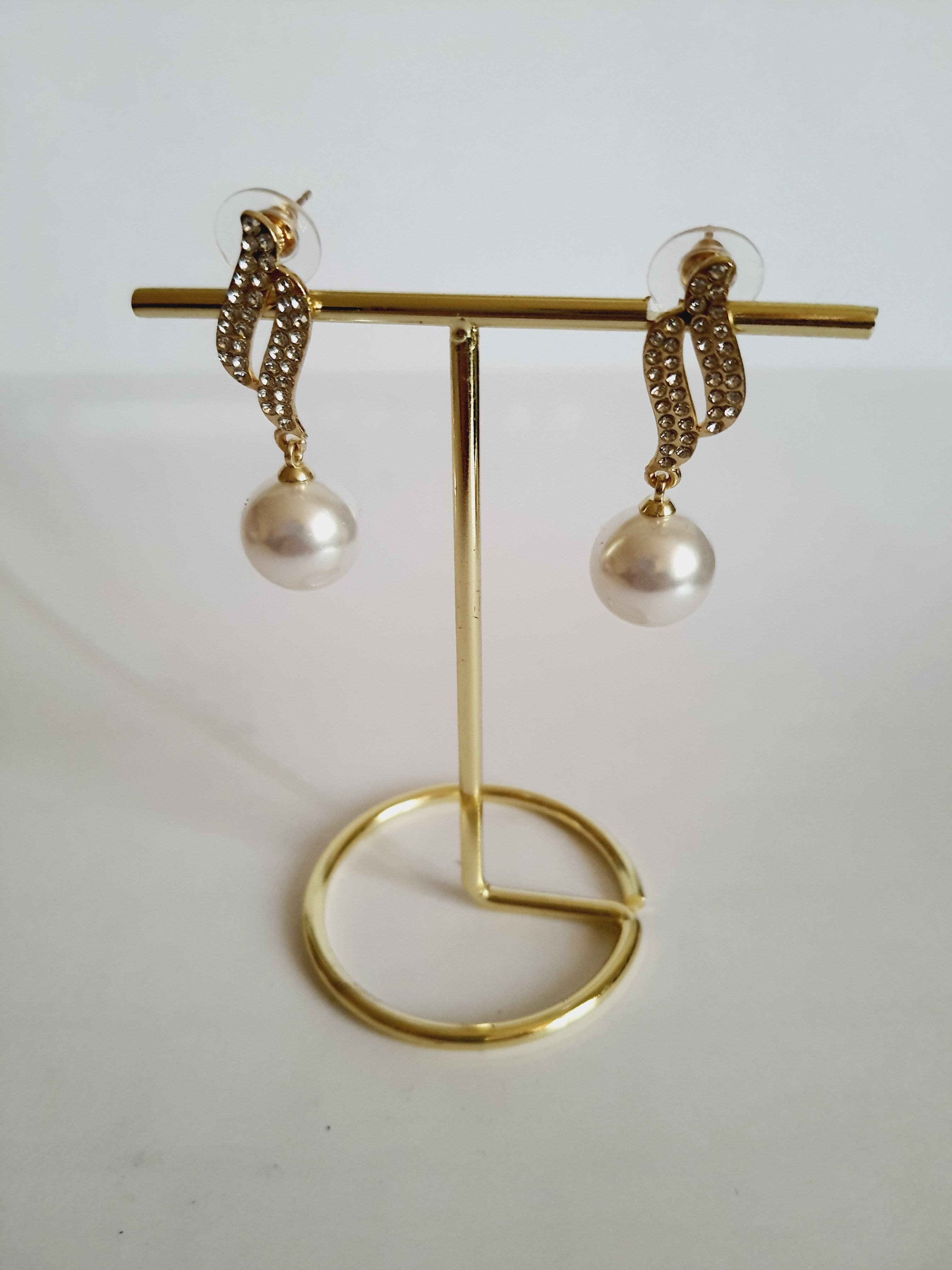 Kolczyki złote ze stali nierdzewnej o długości 4 cm, z dużą białą perłą i złotą falą wysadzaną cyrkoniami, elegancja i blask, Rouge Bizu.