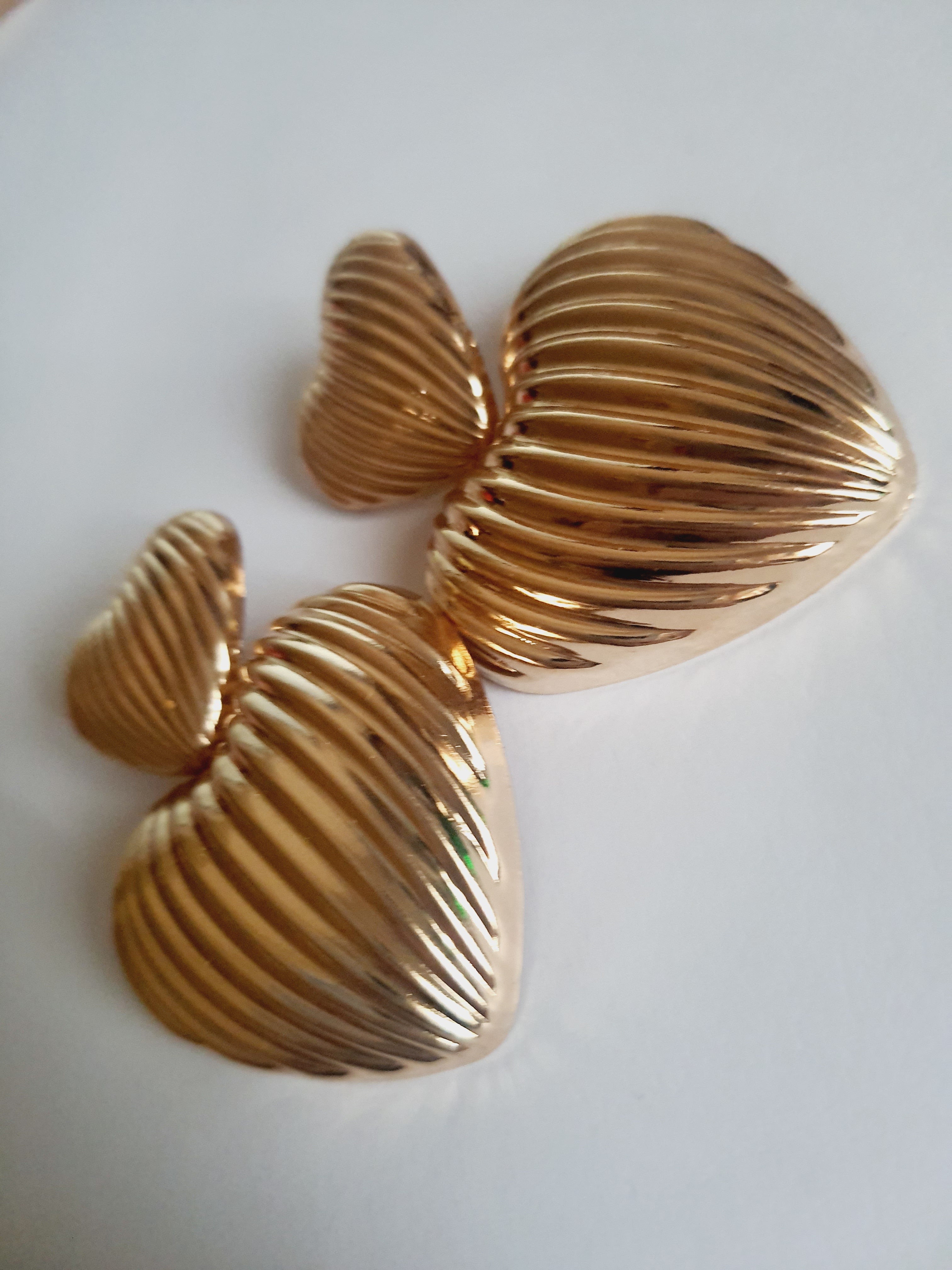 Złote kolczyki w kształcie serc, duże i eleganckie, ze żłobieniami nadającymi im wyjątkowego blasku. Wykonane ze stali nierdzewnej. Rouge Bizu.