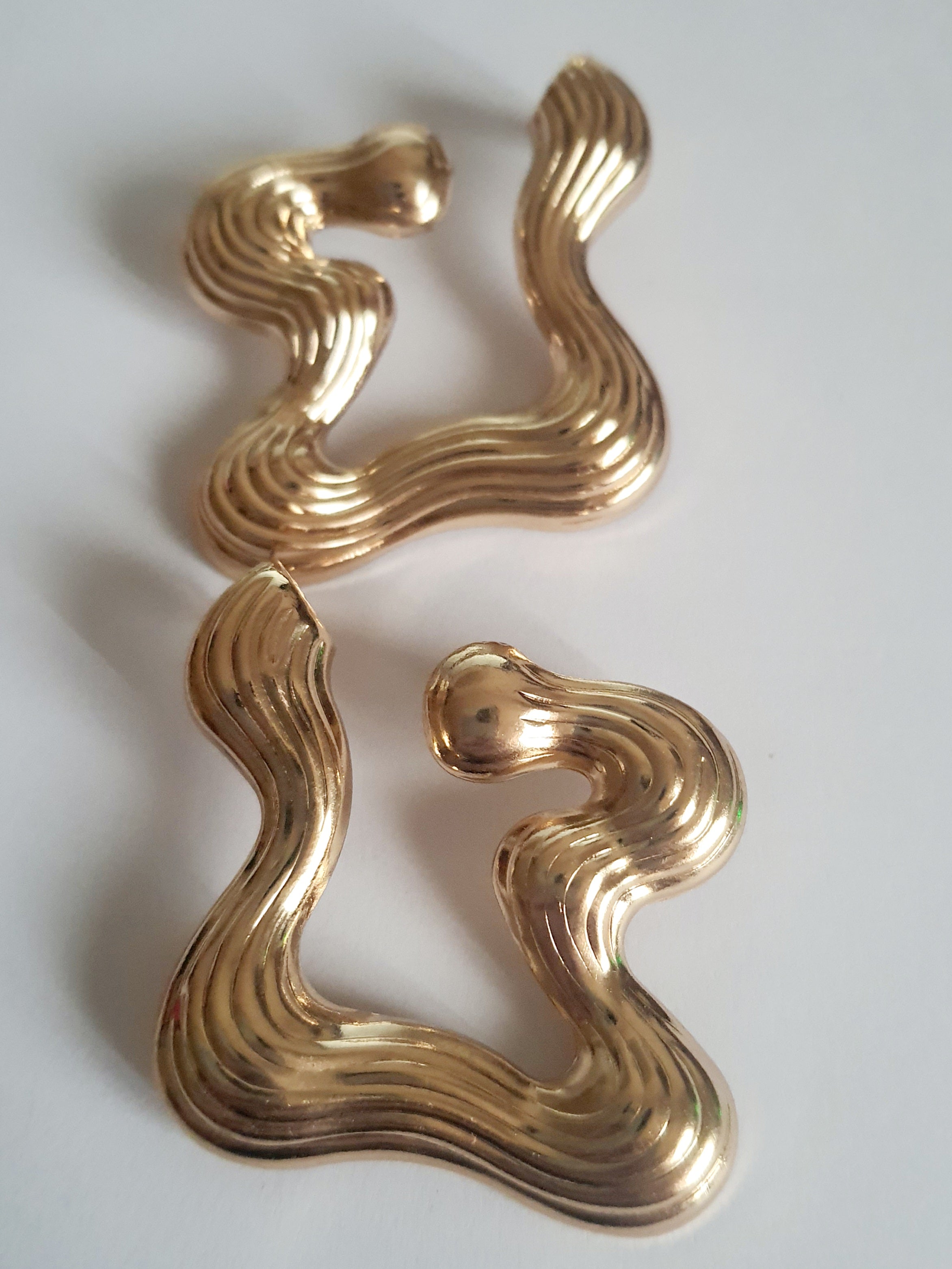 Złote kolczyki falujące o artystycznej, nieregularnej formie, eleganckie i nowoczesne. Stal nierdzewna, długość 5 cm. Rouge Bizu.