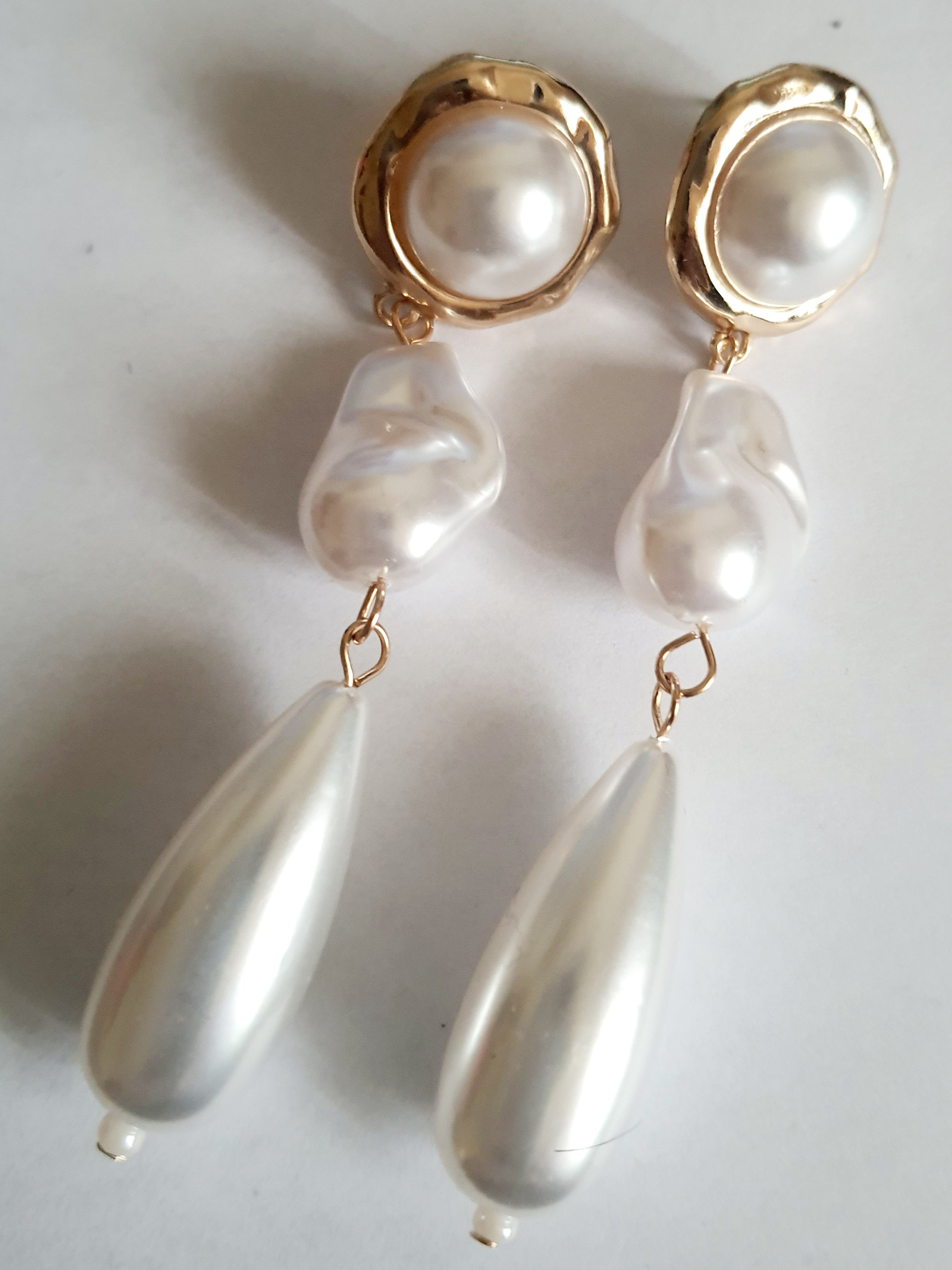 Długie złote kolczyki ze stali nierdzewnej z potrójnymi perłami: okrągłą, nieregularną i kroplą. Styl glamour, klasyczna elegancja. Długość 9 cm. Rouge Bizu.