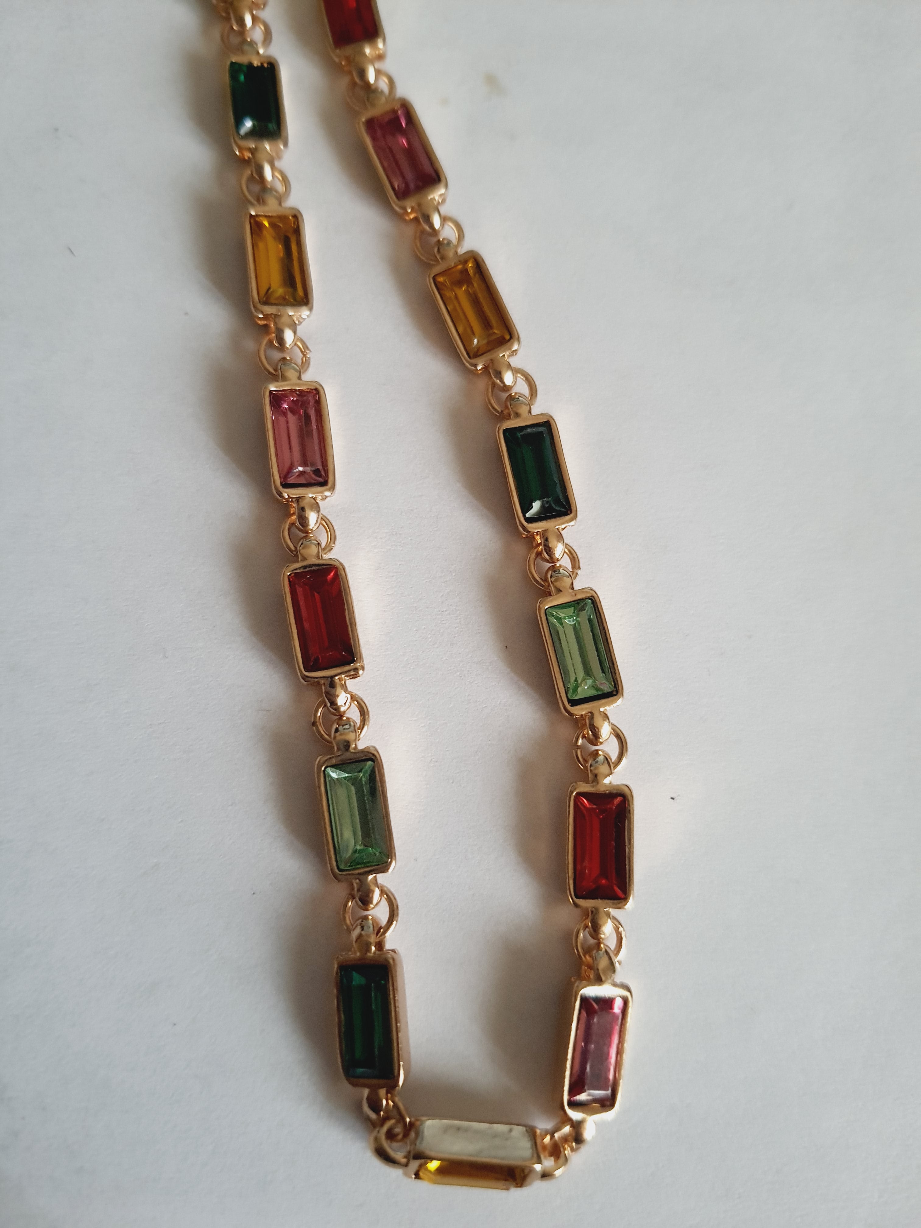 Złoty naszyjnik ze stali nierdzewnej z prostokątnymi, wielobarwnymi kryształami w odcieniach zieleni, czerwieni, różu, złota i turkusu. Długość 41–47 cm. Rouge Bizu.