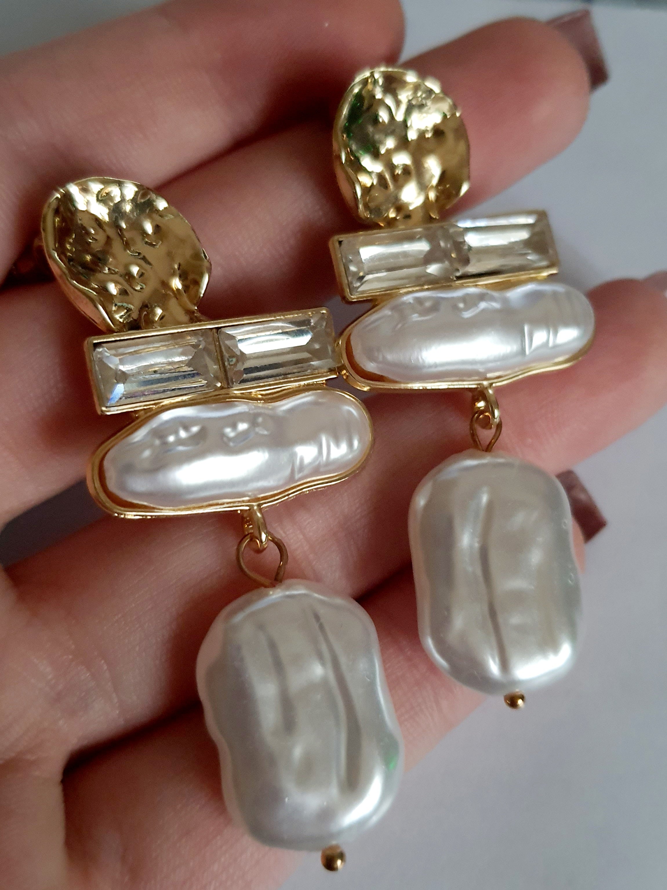 „Złote kolczyki ze stali nierdzewnej o długości 6 cm, zdobione nieregularnymi perłami barokowymi oraz prostokątnymi kryształami, eleganckie i stylowe – Rouge Bizu.”