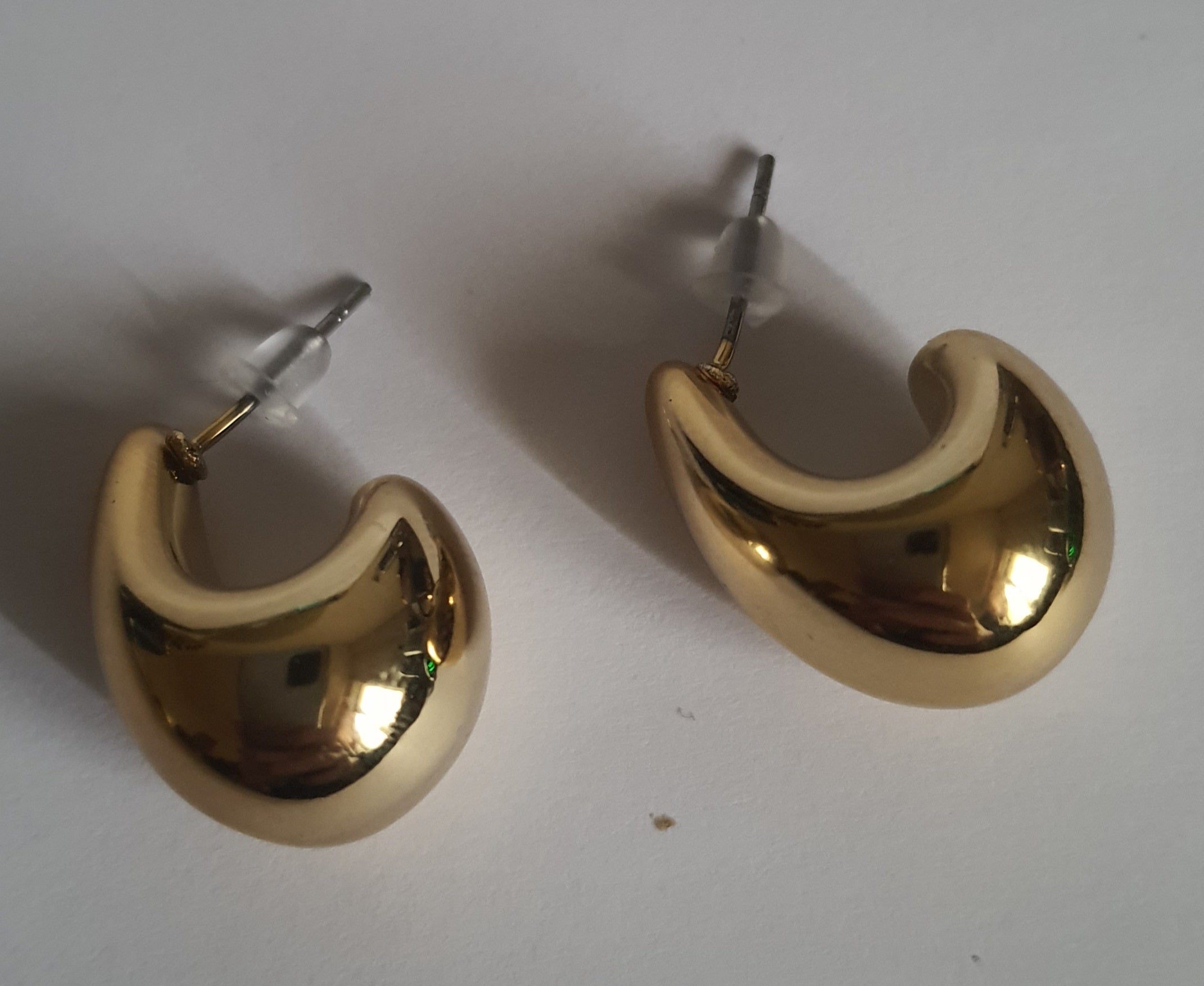 „Złote kolczyki krople o długości 2 cm, wykonane ze stali nierdzewnej, o lśniącej powierzchni w nowoczesnym, organicznym stylu – Rouge Bizu.”