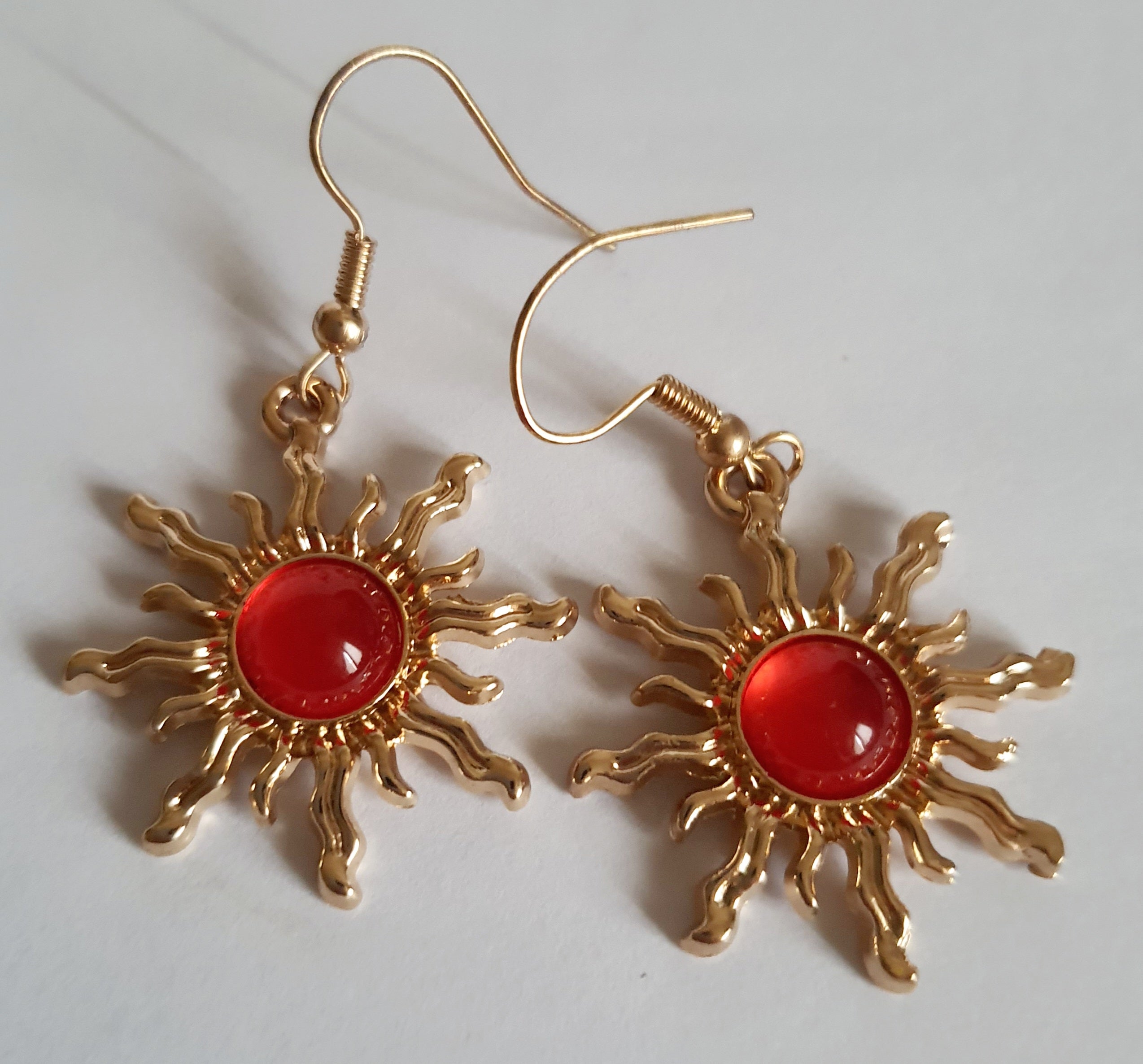 Kolczyki w kształcie słońca ze stali nierdzewnej, złocone, z centralnym czerwonym kamieniem, długość 4 cm, RougeBizu.