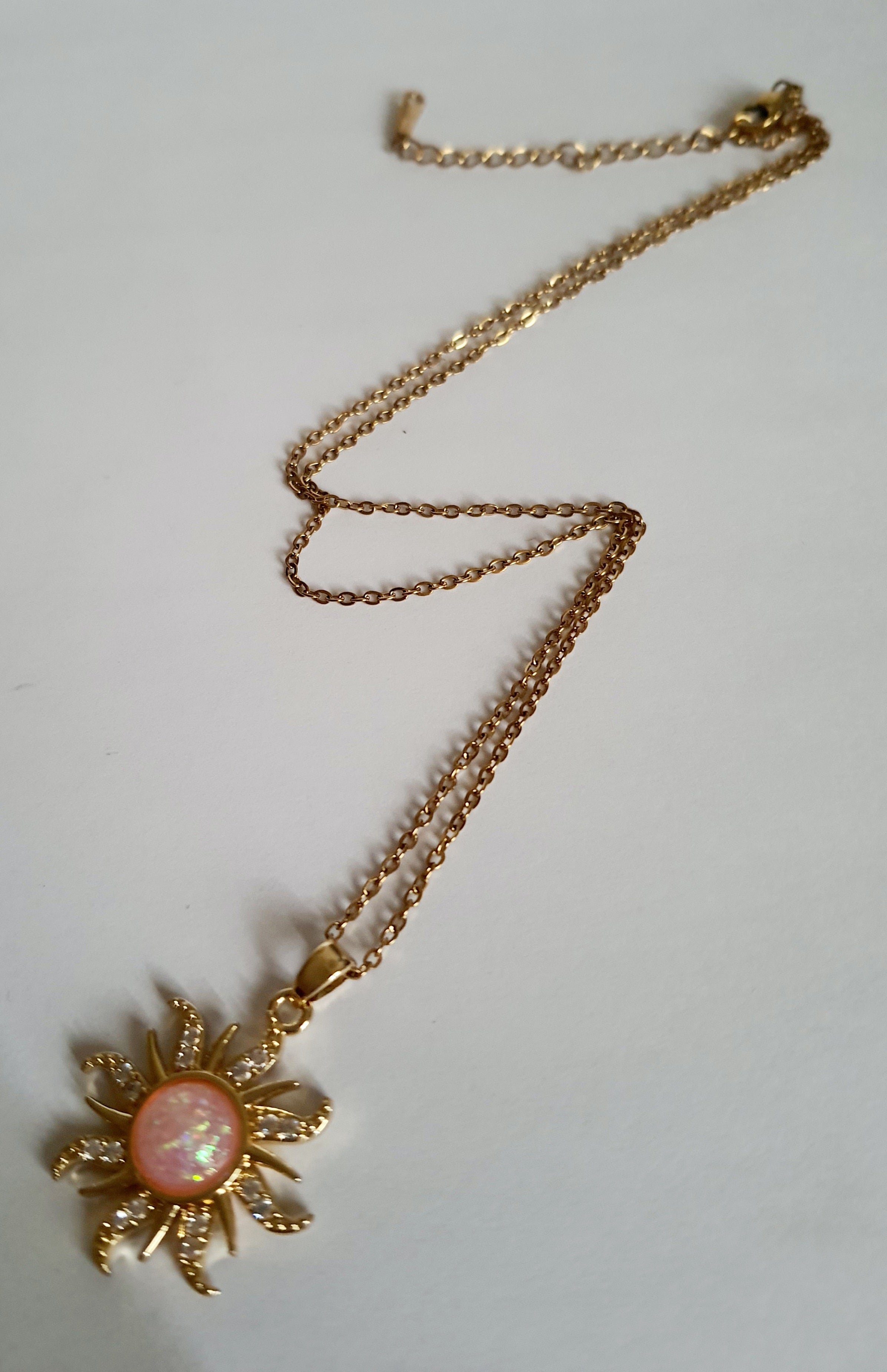 Naszyjnik złocony ze stali nierdzewnej, długość 42–47 cm, zawieszka w kształcie słońca z opalizującym kamieniem i cyrkoniami, RougeBizu.