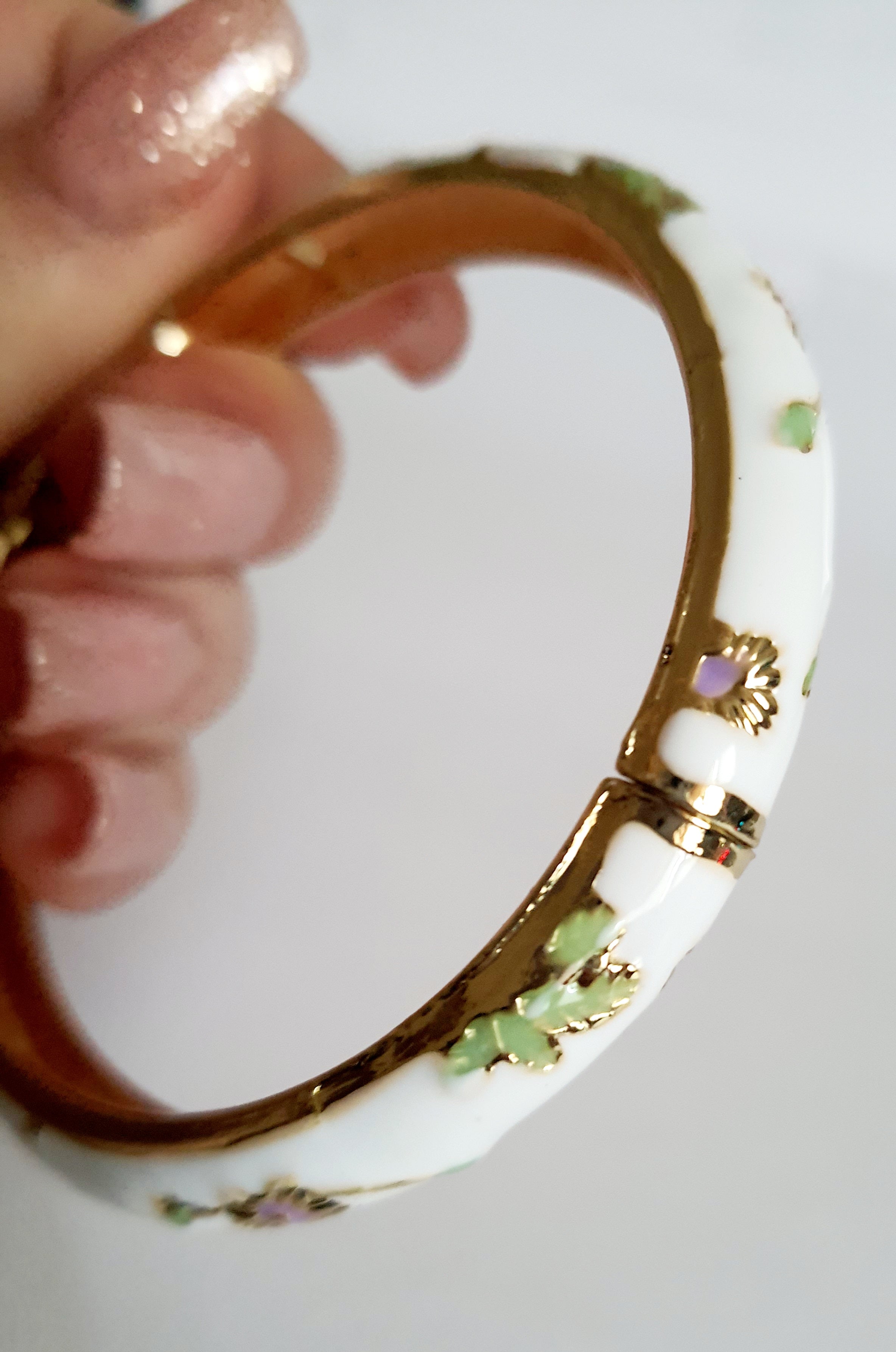 Bransoletka ze stali nierdzewnej, emaliowana na biało, zdobiona złotymi detalami i motywem kwiatowym w kolorach zieleni, czerwieni i różu, średnica 6 cm, Rouge Bizu.