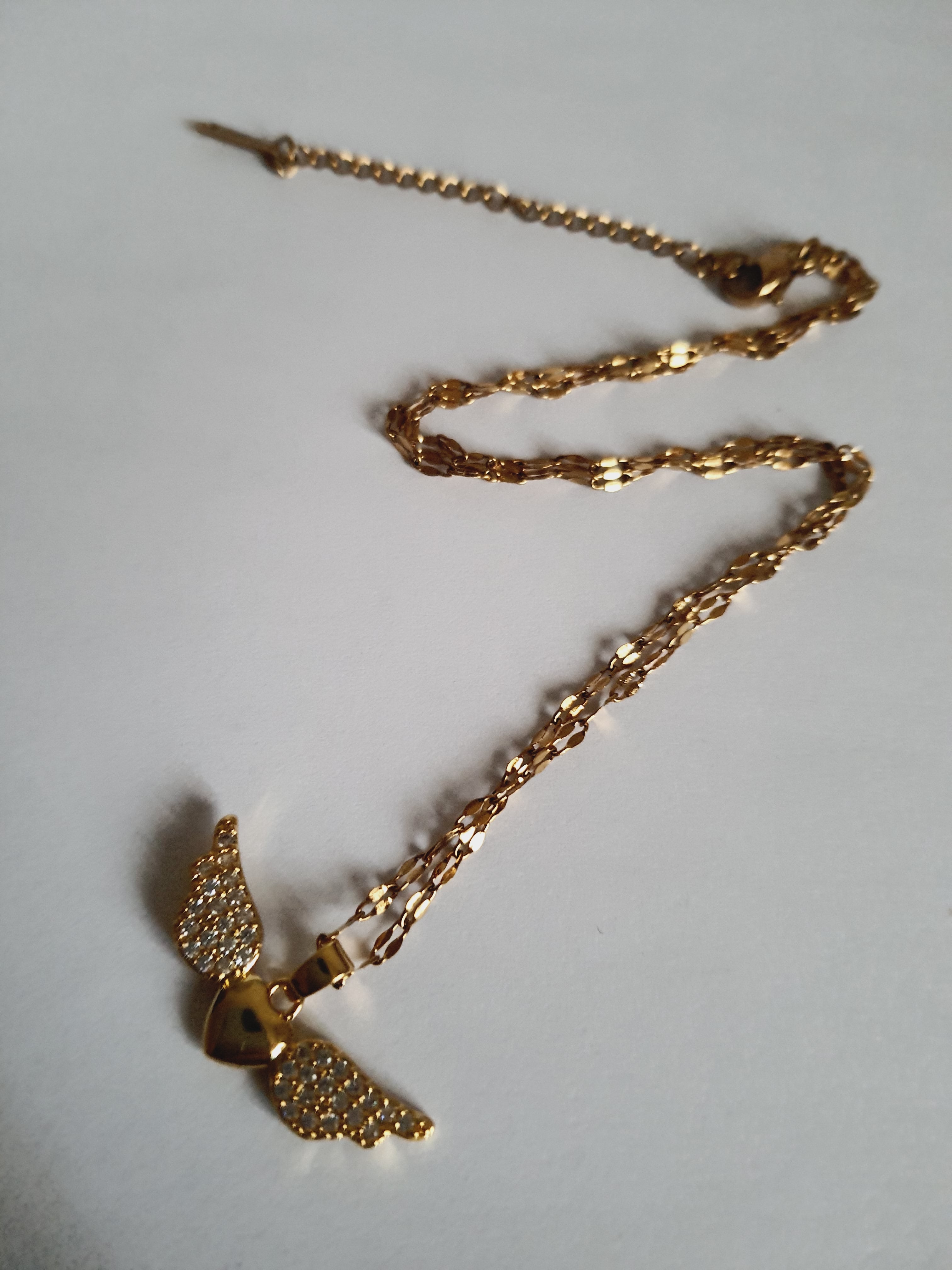 Naszyjnik ze stali nierdzewnej w kolorze złotym, z zawieszką w kształcie serca ze skrzydłami wysadzanymi kryształami, długość łańcuszka 40–45 cm, Rouge Bizu.