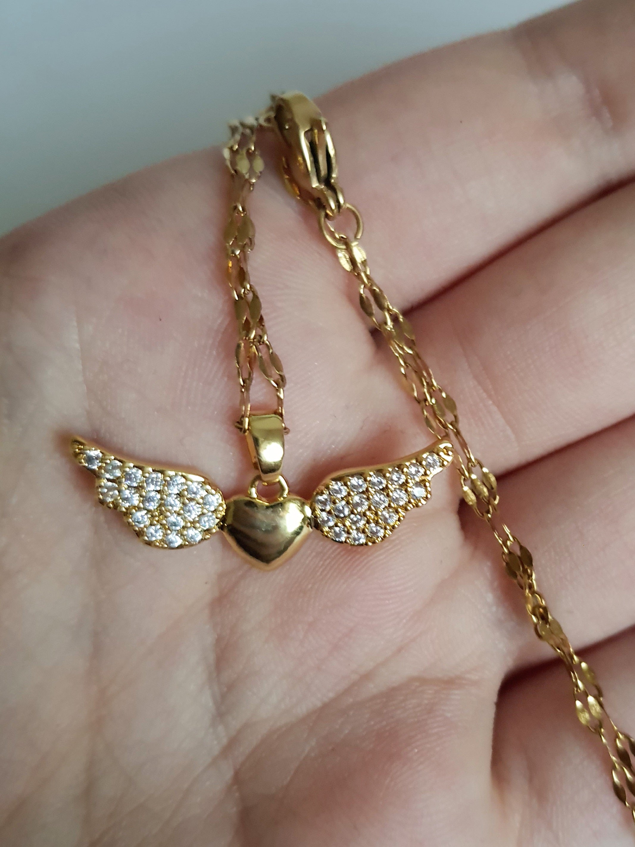 Naszyjnik ze stali nierdzewnej w kolorze złotym, z zawieszką w kształcie serca ze skrzydłami wysadzanymi kryształami, długość łańcuszka 40–45 cm, Rouge Bizu.