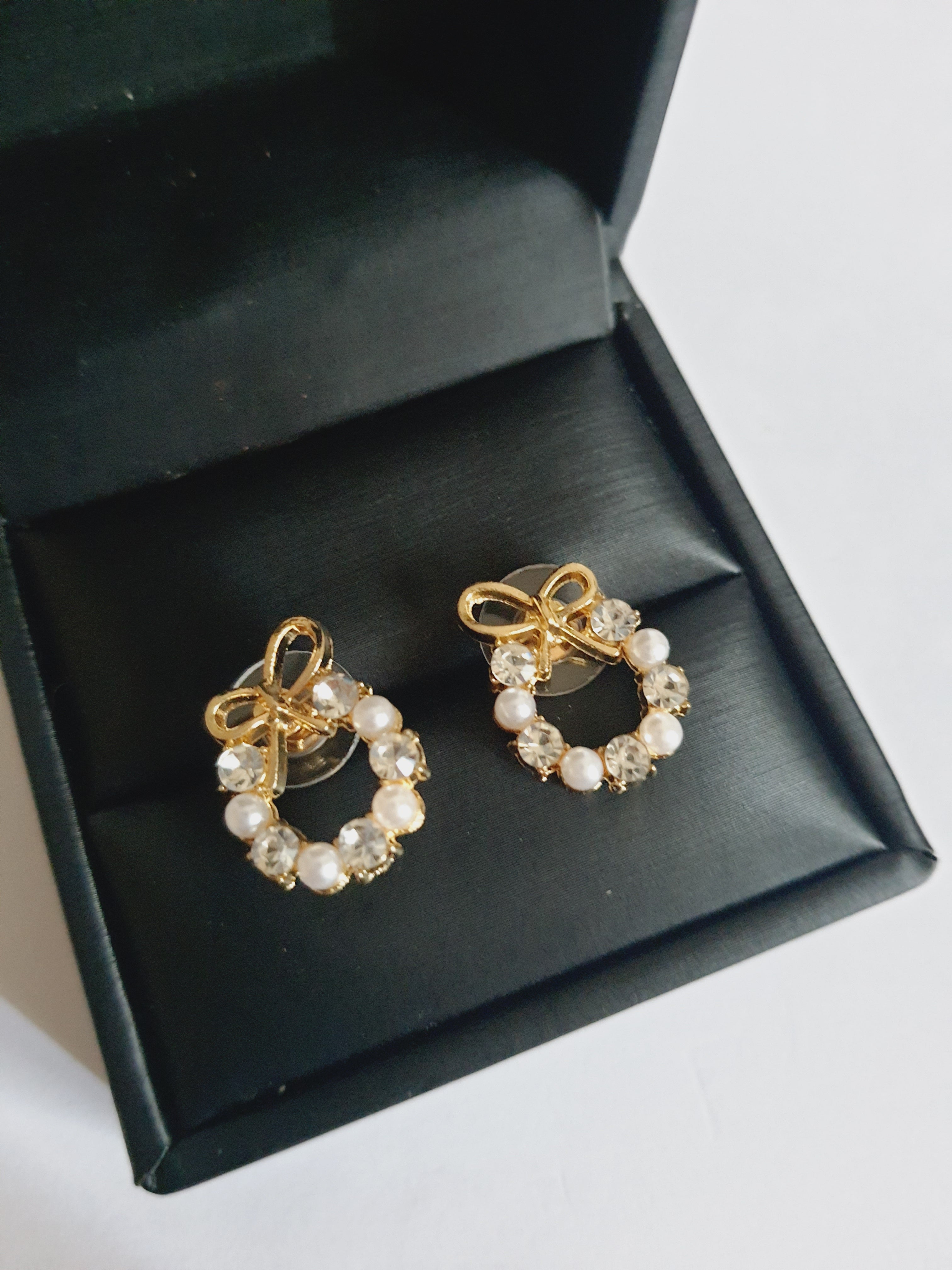 Kolczyki złote ze stali nierdzewnej w kształcie kokardek, zdobione perełkami i transparentnymi kryształkami, długość 2 cm, Rouge Bizu.