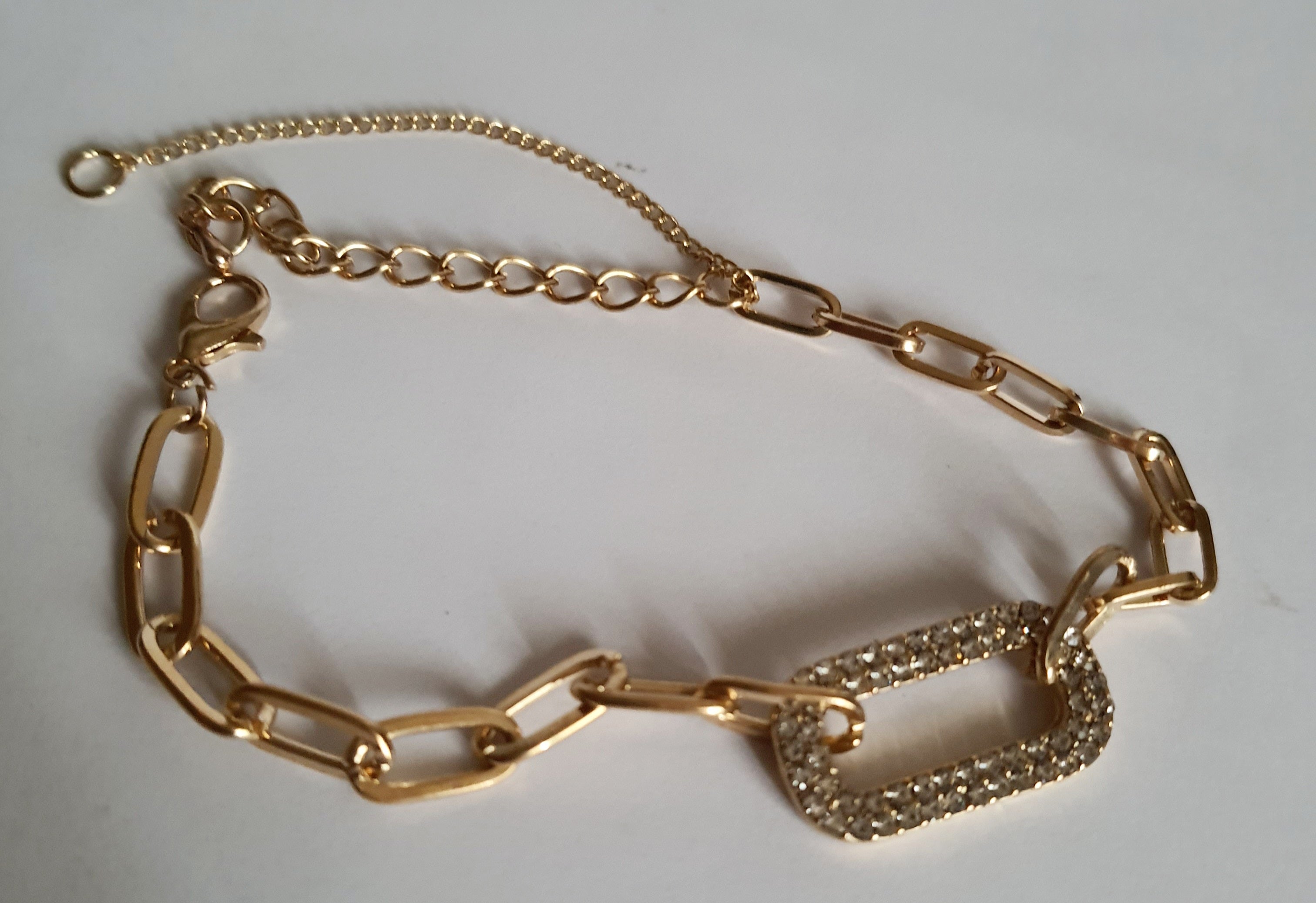 Złota bransoletka ze stali nierdzewnej z łańcuszkowym splotem i centralnym ogniwem wysadzanym transparentnymi kryształami, regulowana długość 17–22 cm, Rouge Bizu.