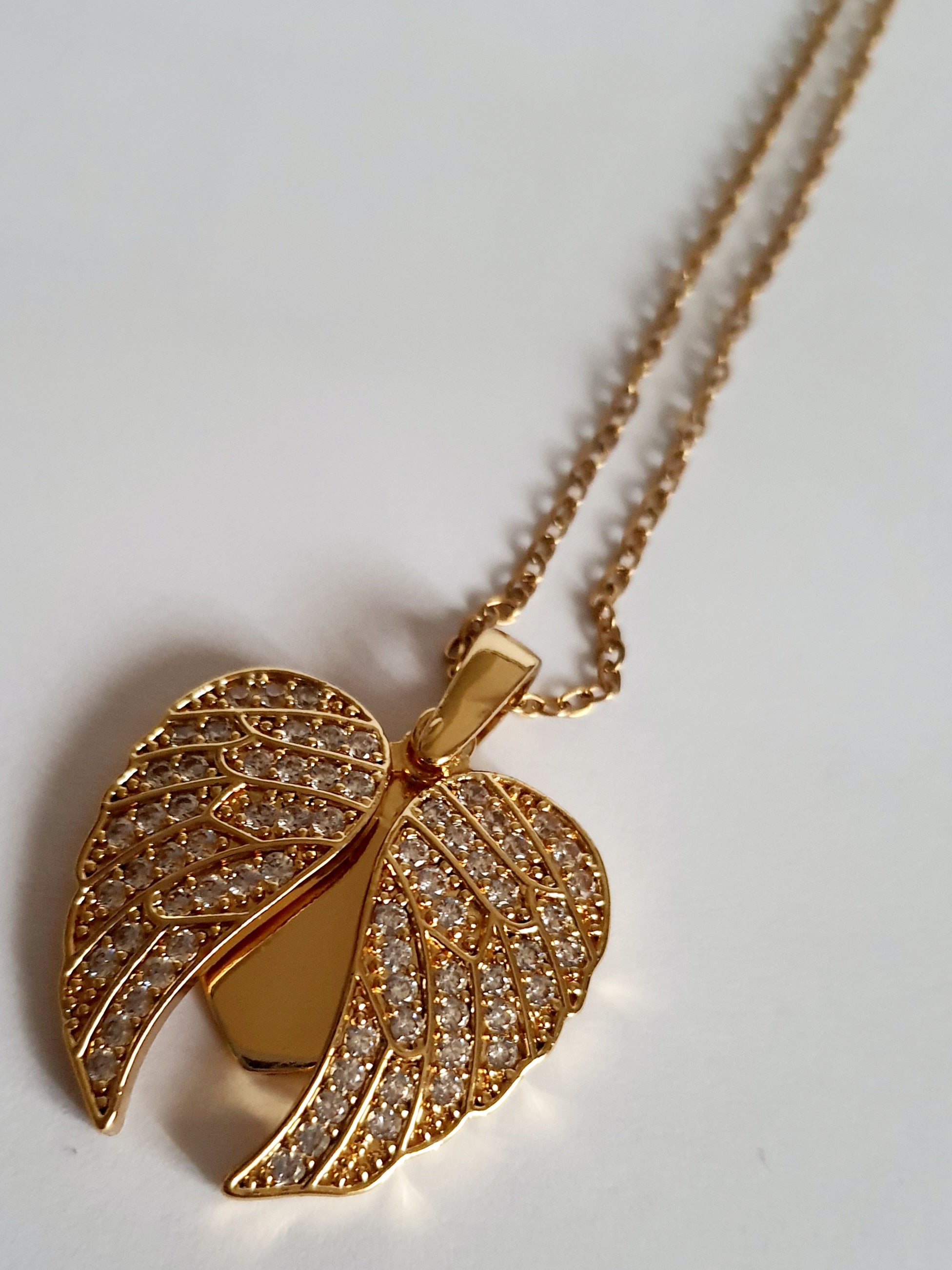 Naszyjnik ze stali nierdzewnej w kolorze złotym, z zawieszką serce i rozkładanymi skrzydłami ozdobionymi kryształkami, regulowana długość 40–45 cm, Rouge Bizu.