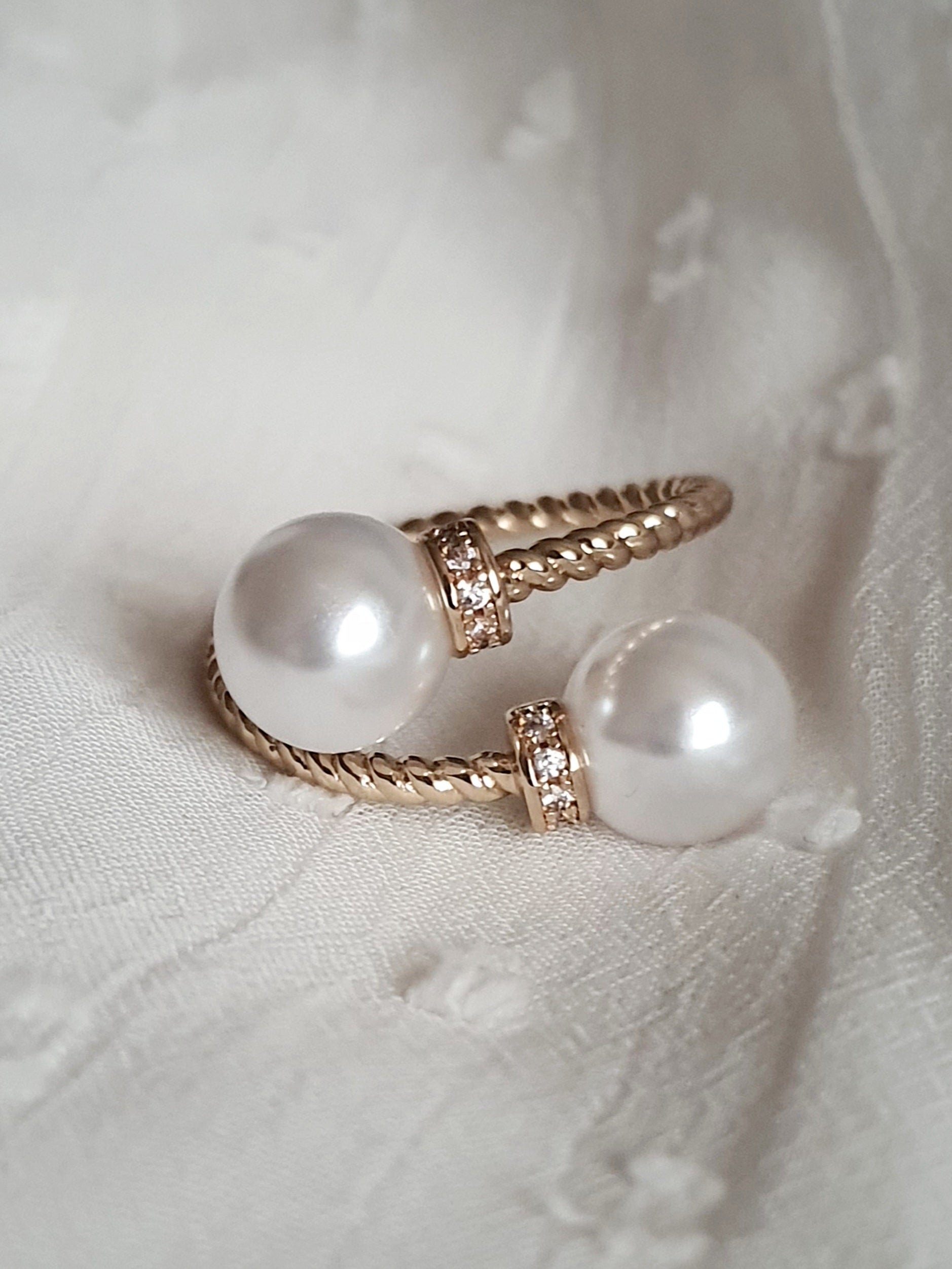 Pierścionek damski ze stali nierdzewnej, złoty, rozmiar 19 mm, zdobiony dwiema syntetycznymi perłami i drobnymi cyrkoniami, pleciona obrączka, elegancki styl glamour, Rouge Bizu.