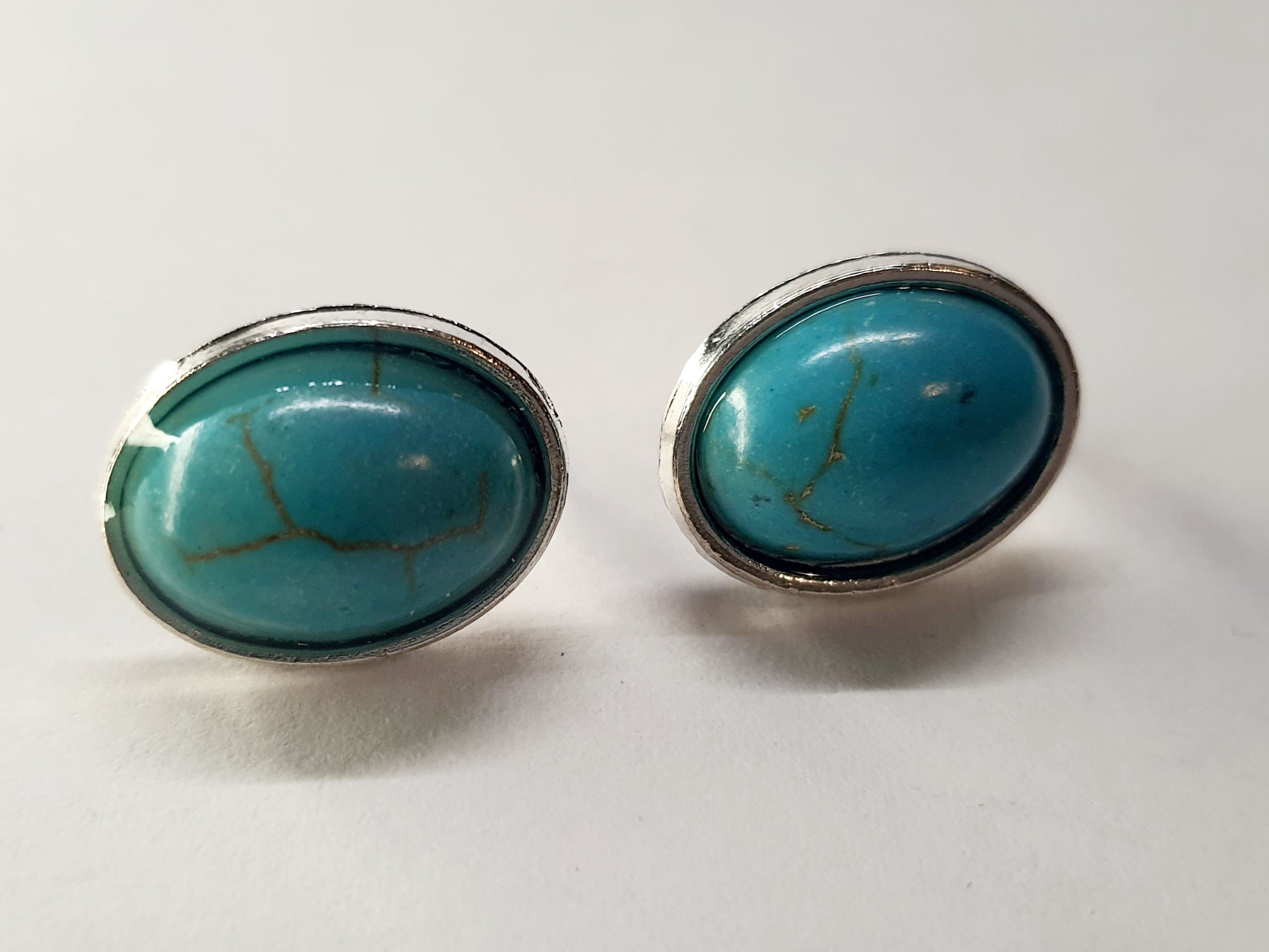 Kolczyki owalne z turkusowym kamieniem w srebrnej oprawie. Średnica 1,8 cm. Styl minimalistyczny, elegancki. Stal nierdzewna, stal chirurgiczna, wodoodporne, hipoalergiczne, jakość premium. Rouge Bizu.