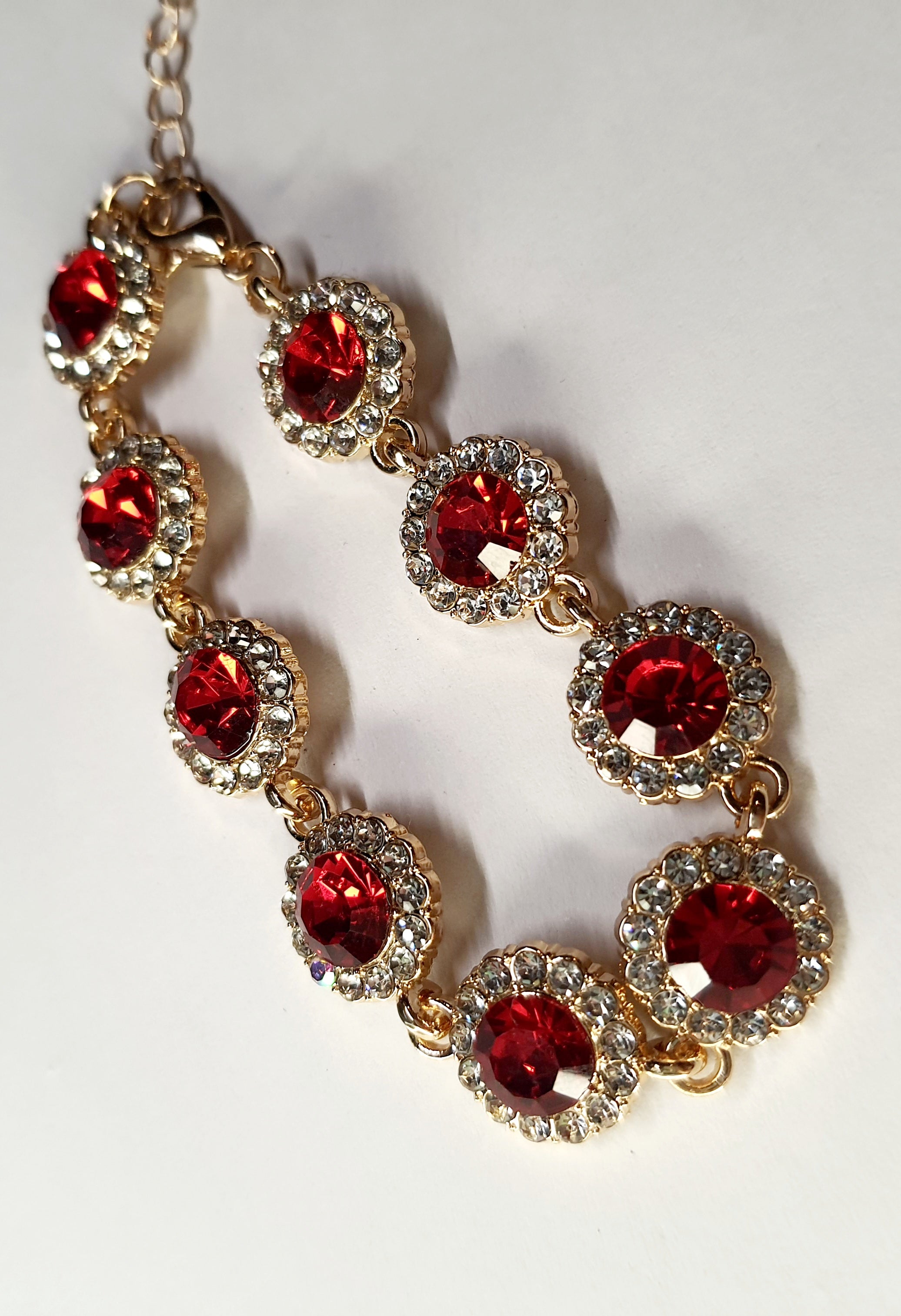 Bransoletka z czerwonymi kamieniami w złotej oprawie, długość regulowana 15–20 cm, styl glamour i elegancki. Stal nierdzewna, stal chirurgiczna, wodoodporne, hipoalergiczne, jakość premium, Rouge Bizu.