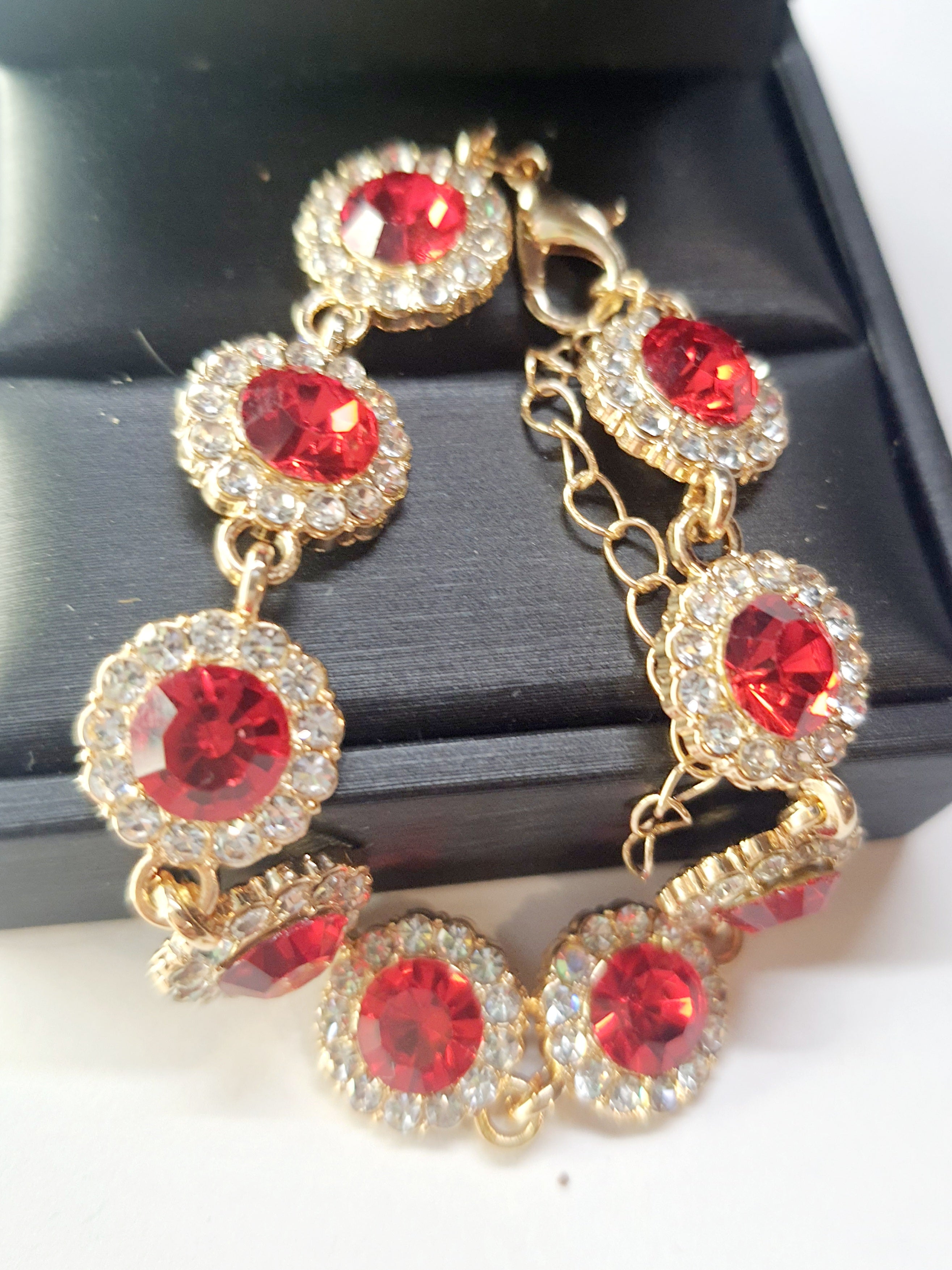 Bransoletka z czerwonymi kamieniami w złotej oprawie, długość regulowana 15–20 cm, styl glamour i elegancki. Stal nierdzewna, stal chirurgiczna, wodoodporne, hipoalergiczne, jakość premium, Rouge Bizu.