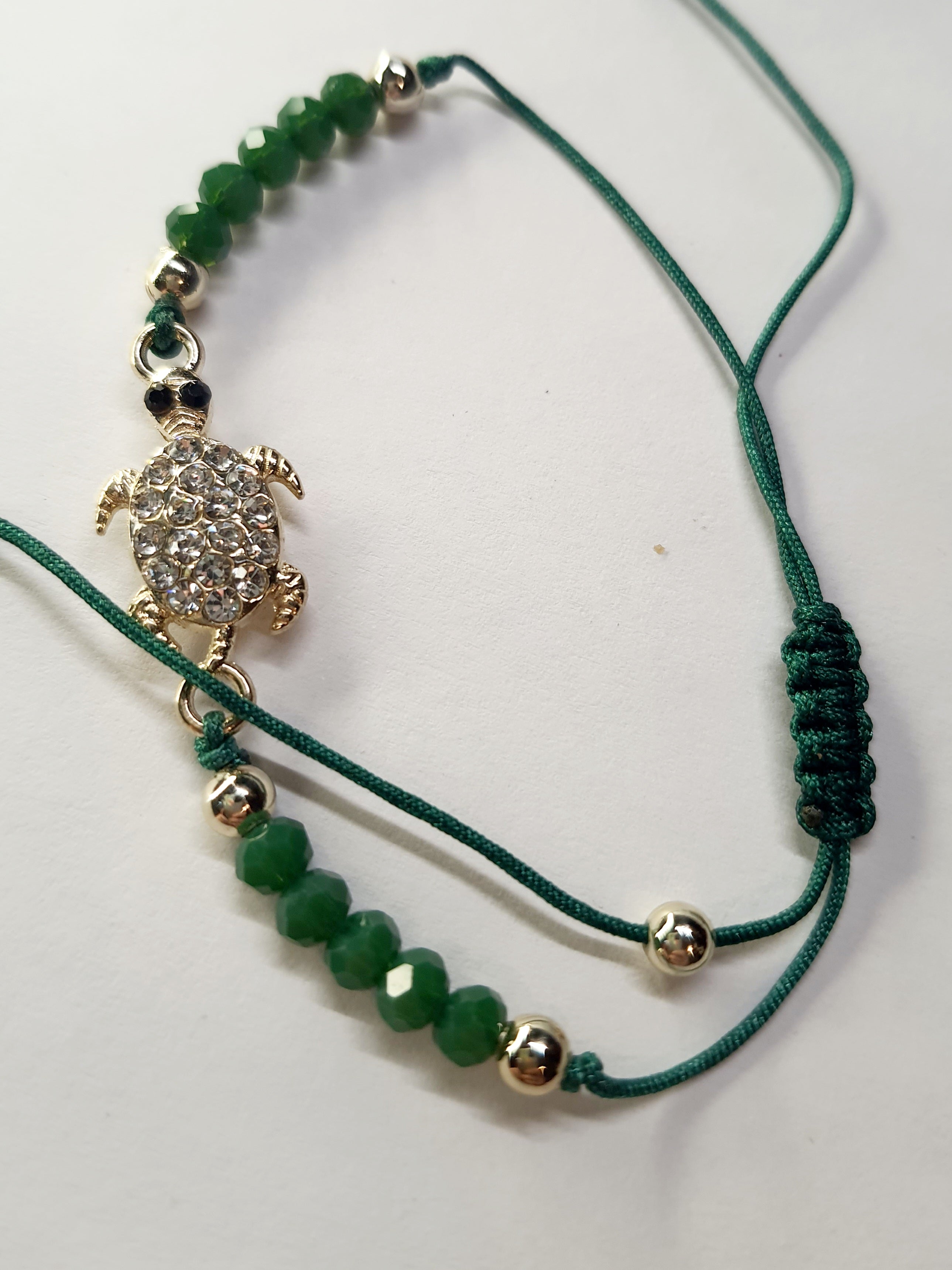 Bransoletka z zawieszką w kształcie żółwia wysadzanego cyrkoniami na zielonym sznurku z zielonymi koralikami. Styl boho, talizman szczęścia i harmonii. Wodoodporne, hipoalergiczne, jakość premium. Rouge Bizu.
