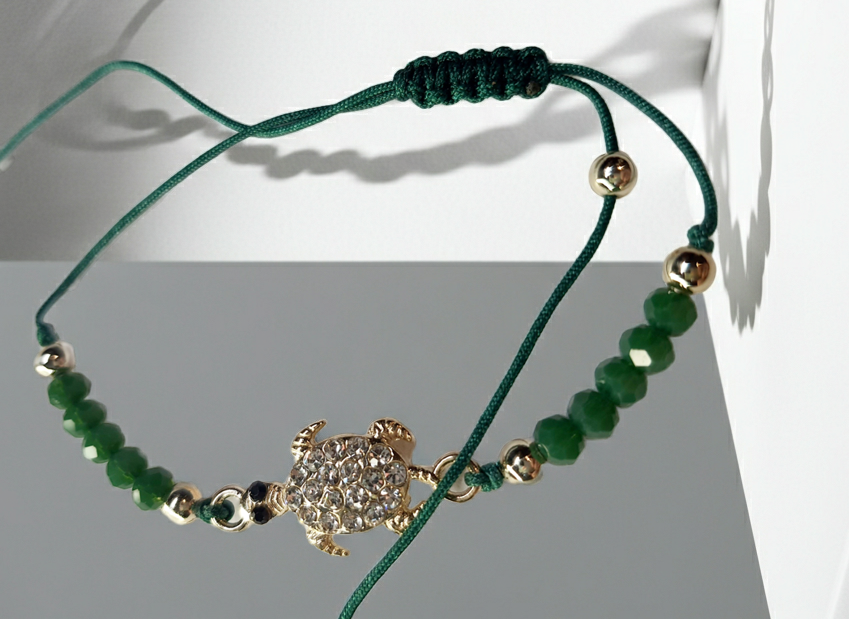 Bransoletka z zawieszką w kształcie żółwia wysadzanego cyrkoniami na zielonym sznurku z zielonymi koralikami. Styl boho, talizman szczęścia i harmonii. Wodoodporne, hipoalergiczne, jakość premium. Rouge Bizu.