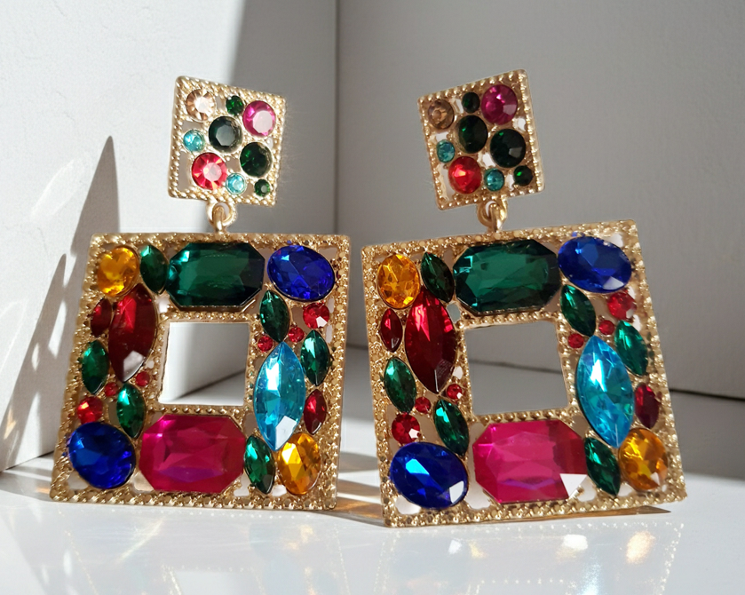 Złote kolczyki ze stali nierdzewnej w kształcie kwadratu, bogato zdobione wielobarwnymi kryształami w odcieniach granatu, zieleni, różu, czerwieni, turkusu i złota. Styl glamour, długość 6 cm. Rouge Bizu.