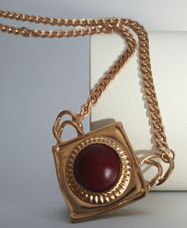 Naszyjnik ze stali nierdzewnej w kolorze złota, z geometryczną zawieszką w kształcie rombu i czerwonym kamieniem pośrodku. Styl elegancki, kobiecy, długość regulowana 44,5–54,5 cm. Rouge Bizu.