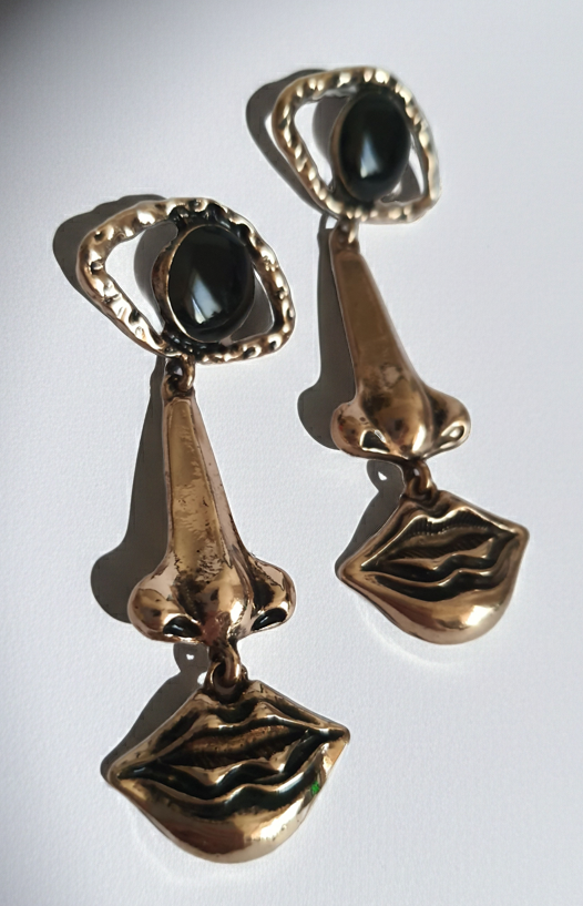 Wiszące kolczyki 7 cm ze stali nierdzewnej w kolorze złotym w kształcie oka, nosa i ust, z czarnym kamieniem w centrum oka. Rouge Bizu, stal nierdzewna, stal chirurgiczna.