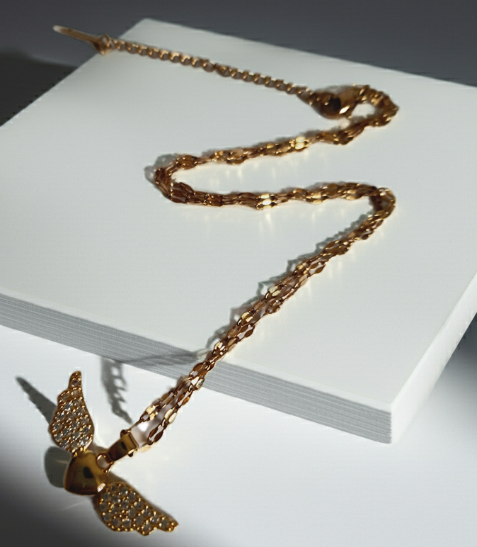 Naszyjnik ze stali nierdzewnej w kolorze złotym, z zawieszką w kształcie serca ze skrzydłami wysadzanymi kryształami, długość łańcuszka 40–45 cm, Rouge Bizu.