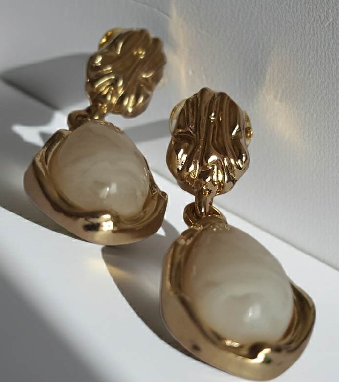 „Złote kolczyki ze stali nierdzewnej o długości 3 cm, zdobione perłowym kaboszonem w kształcie kropli, eleganckie i klasyczne – Rouge Bizu.”