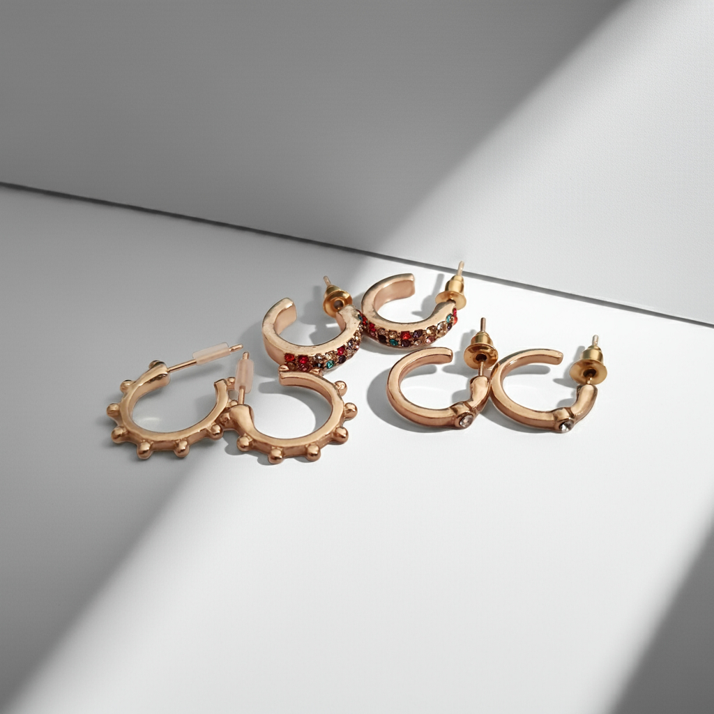 Zestaw 3 par złotych kolczyków typu kółka: kolorowe cyrkonie (1,5 cm), wypustki (1,5 cm), klasyczne z cyrkonią (1 cm). Zapięcie na sztyft. Rouge bizu