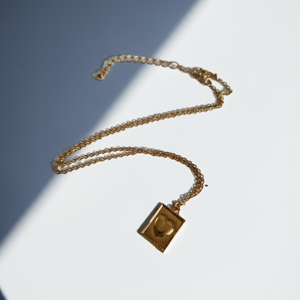 Złocony łańcuszek ze stali chirurgicznej, regulowana długość 38–46,5 cm, prostokątna zawieszka z sercem i promienistym wzorem, RougeBizu.