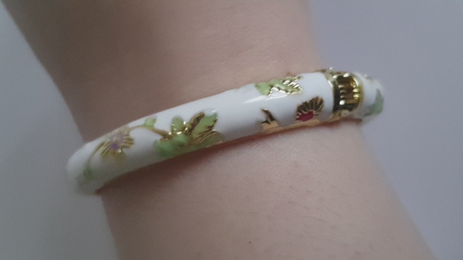 Bransoletka ze stali nierdzewnej, emaliowana na biało, zdobiona złotymi detalami i motywem kwiatowym w kolorach zieleni, czerwieni i różu, średnica 6 cm, Rouge Bizu.