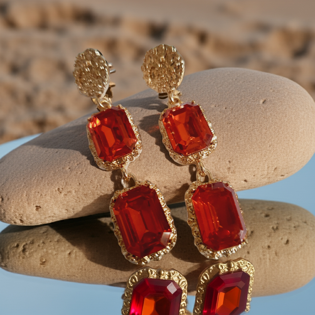 Długie kolczyki ze stali nierdzewnej w stylu glamour, ozdobione dużymi czerwonymi kamieniami w złotej oprawie. Elegancja, luksus i ognisty blask. Długość 7 cm. Rouge Bizu.