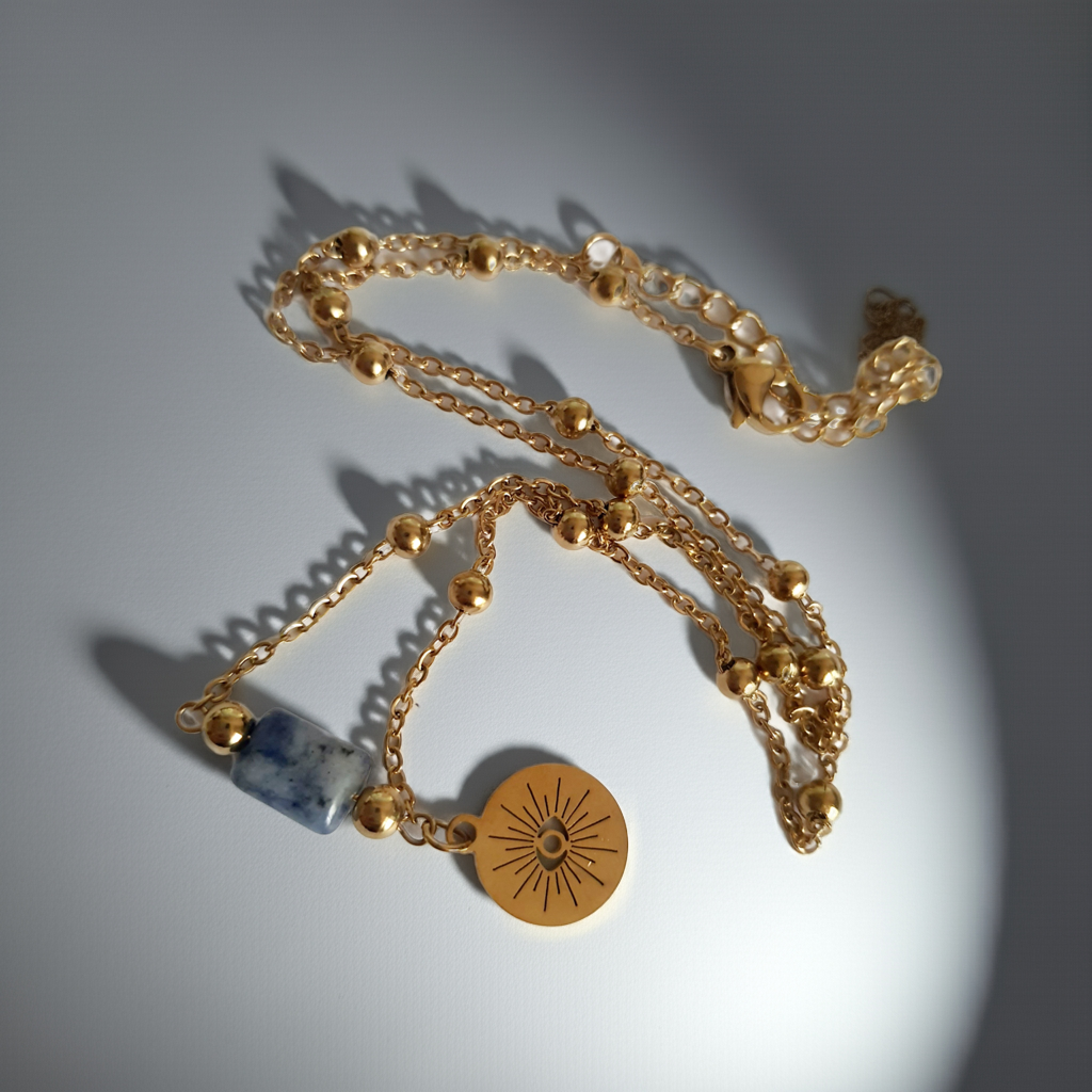 Złoty łańcuszek ze stali nierdzewnej o długości 40–45 cm z granatowym kamieniem i okrągłym talizmanem w kształcie słońca. Styl boho, minimalistyczny, duchowy. Rouge Bizu.