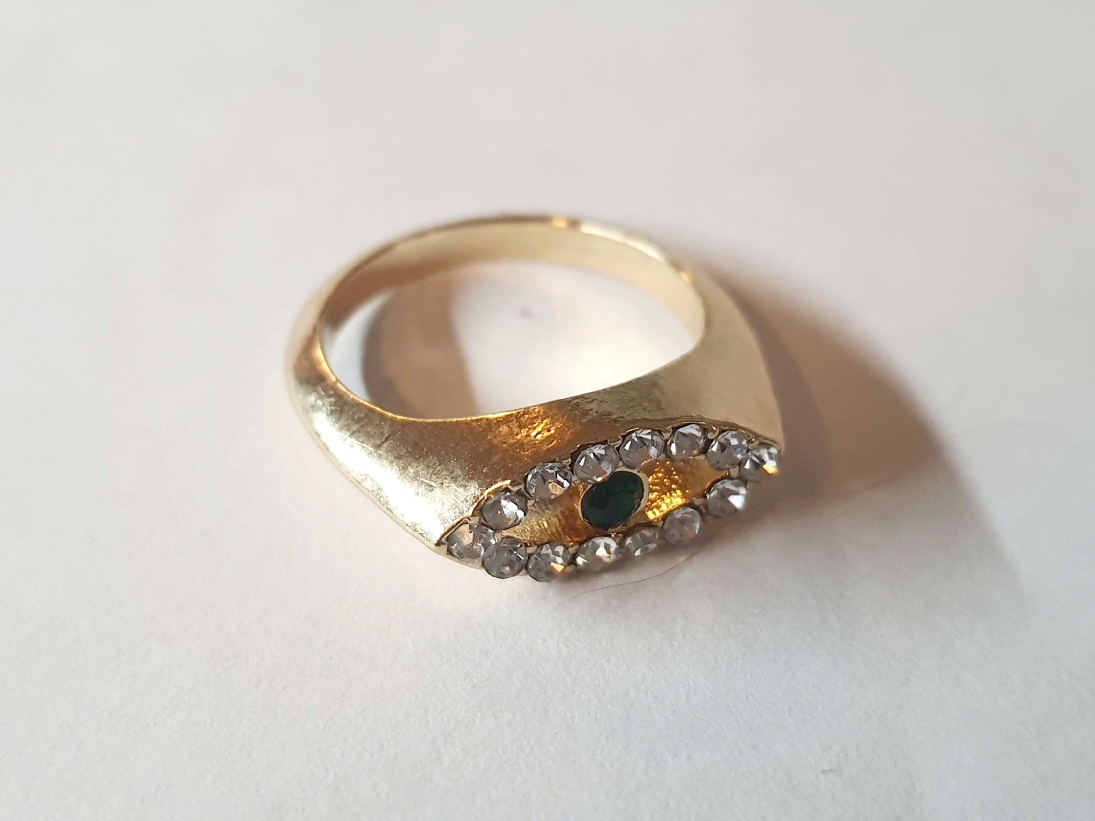 „Złoty pierścionek ze stali nierdzewnej, rozmiar 17 mm, motyw oka z cyrkoniami i zielonym kamieniem. Modny trend evil eye w stylu glamour – Rouge Bizu.”