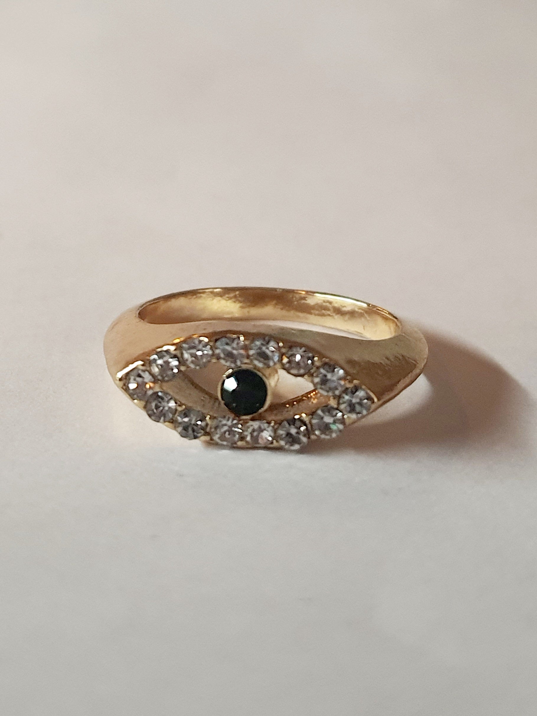 „Złoty pierścionek ze stali nierdzewnej, rozmiar 17 mm, motyw oka z cyrkoniami i zielonym kamieniem. Modny trend evil eye w stylu glamour – Rouge Bizu.”