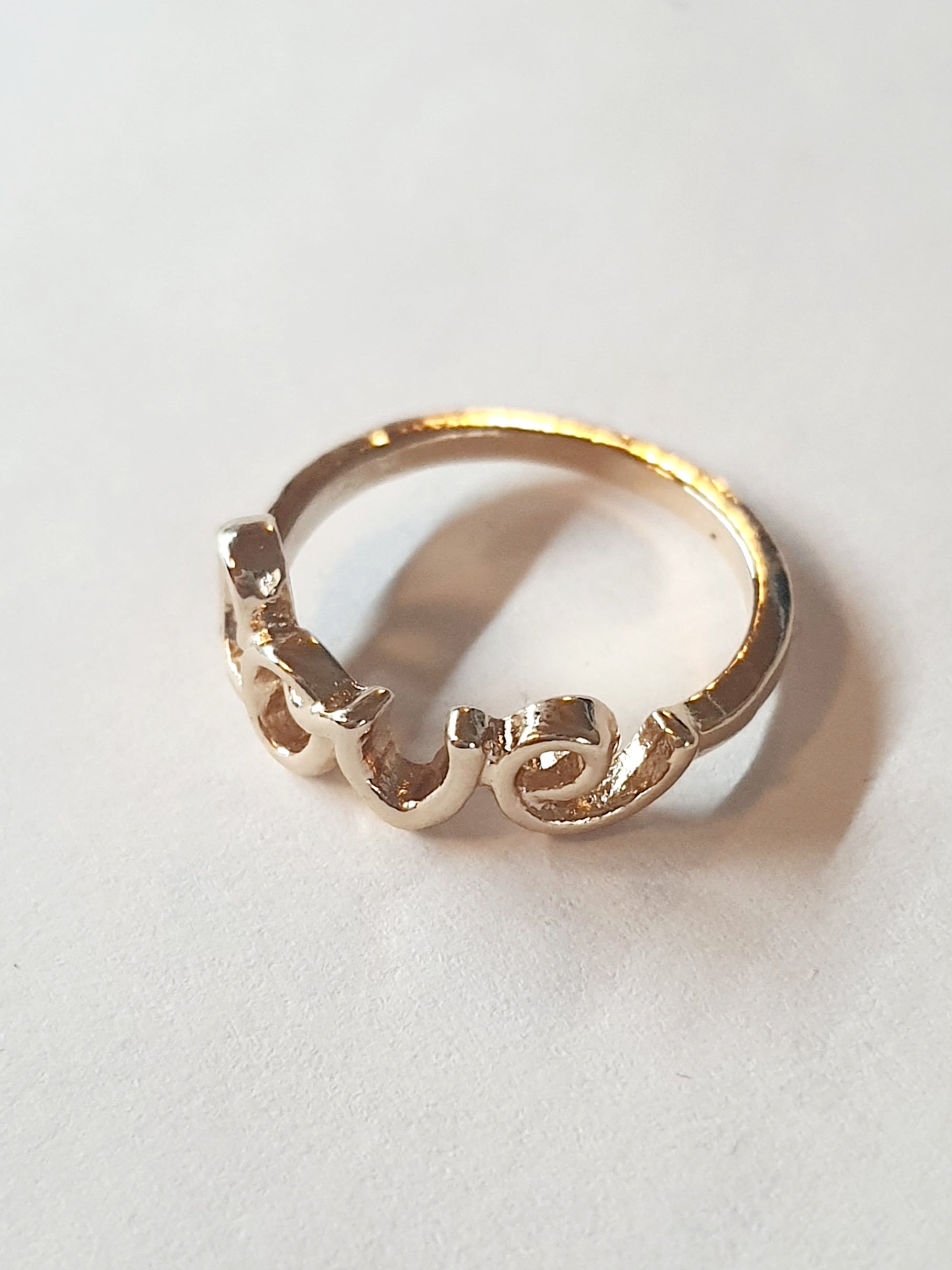 Pierścionek ze stali nierdzewnej w kolorze złotym, z napisem LOVE w otwartej formie. Romantyczny i elegancki, rozmiar 17 mm. Rouge Bizu.