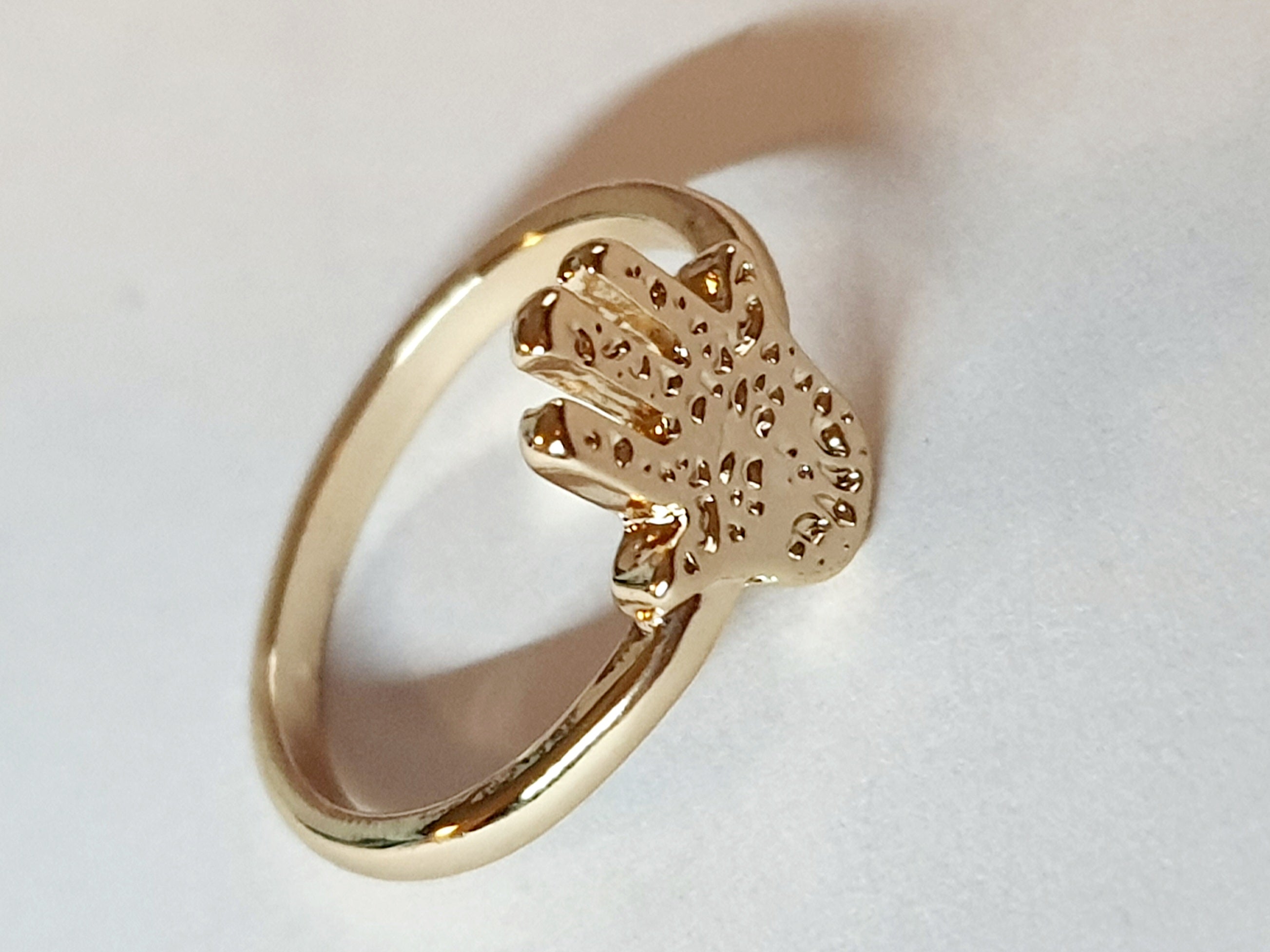 Złoty pierścionek ze stali nierdzewnej z motywem dłoni Hamsa (Ręki Fatimy). Orientalny i symboliczny design. Rozmiar 16 mm. Rouge Bizu.