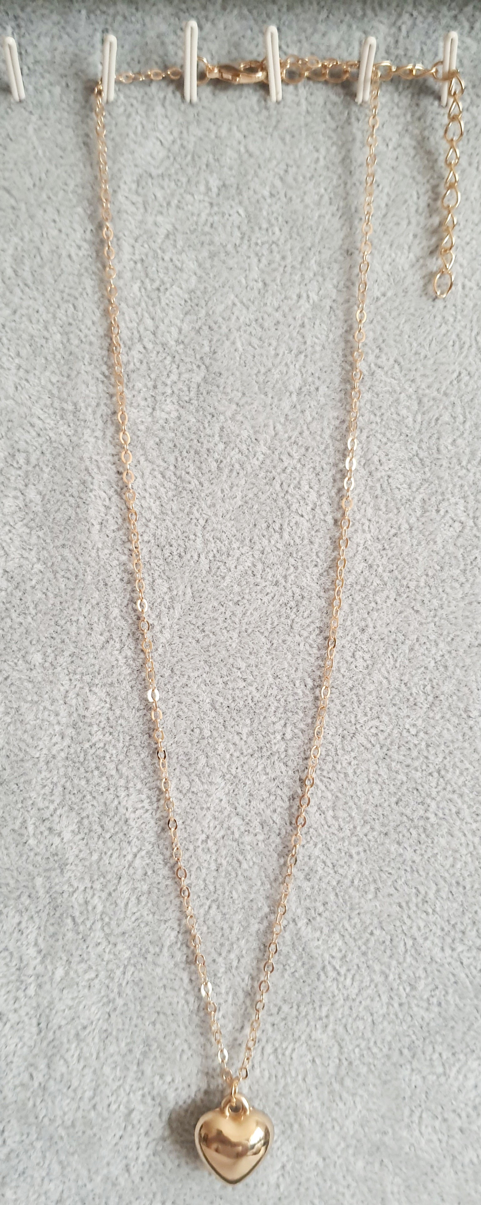 Złoty naszyjnik ze stali nierdzewnej z zawieszką w kształcie serca na jasnym tle,  długośc regulowana. prostota i elegancja. rougebizu