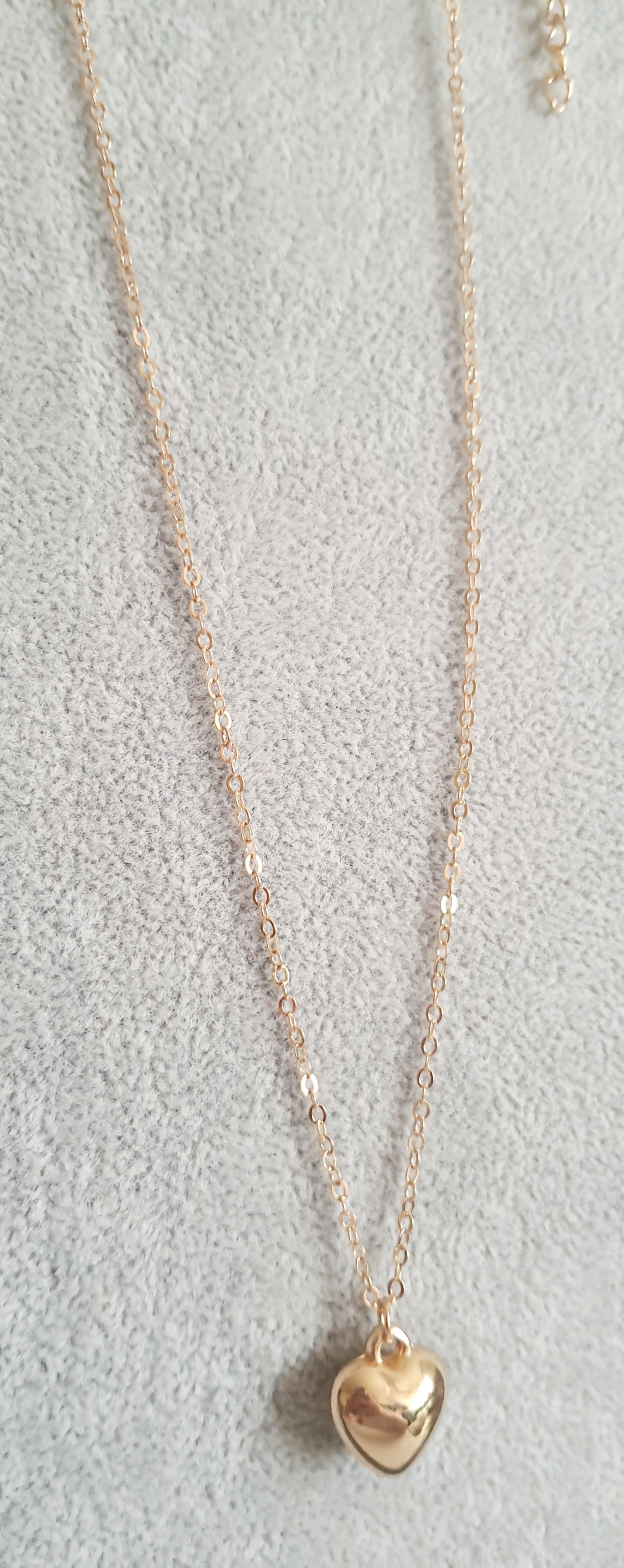 Złoty naszyjnik ze stali nierdzewnej z zawieszką w kształcie serca na jasnym tle,  długośc regulowana. prostota i elegancja. rougebizu