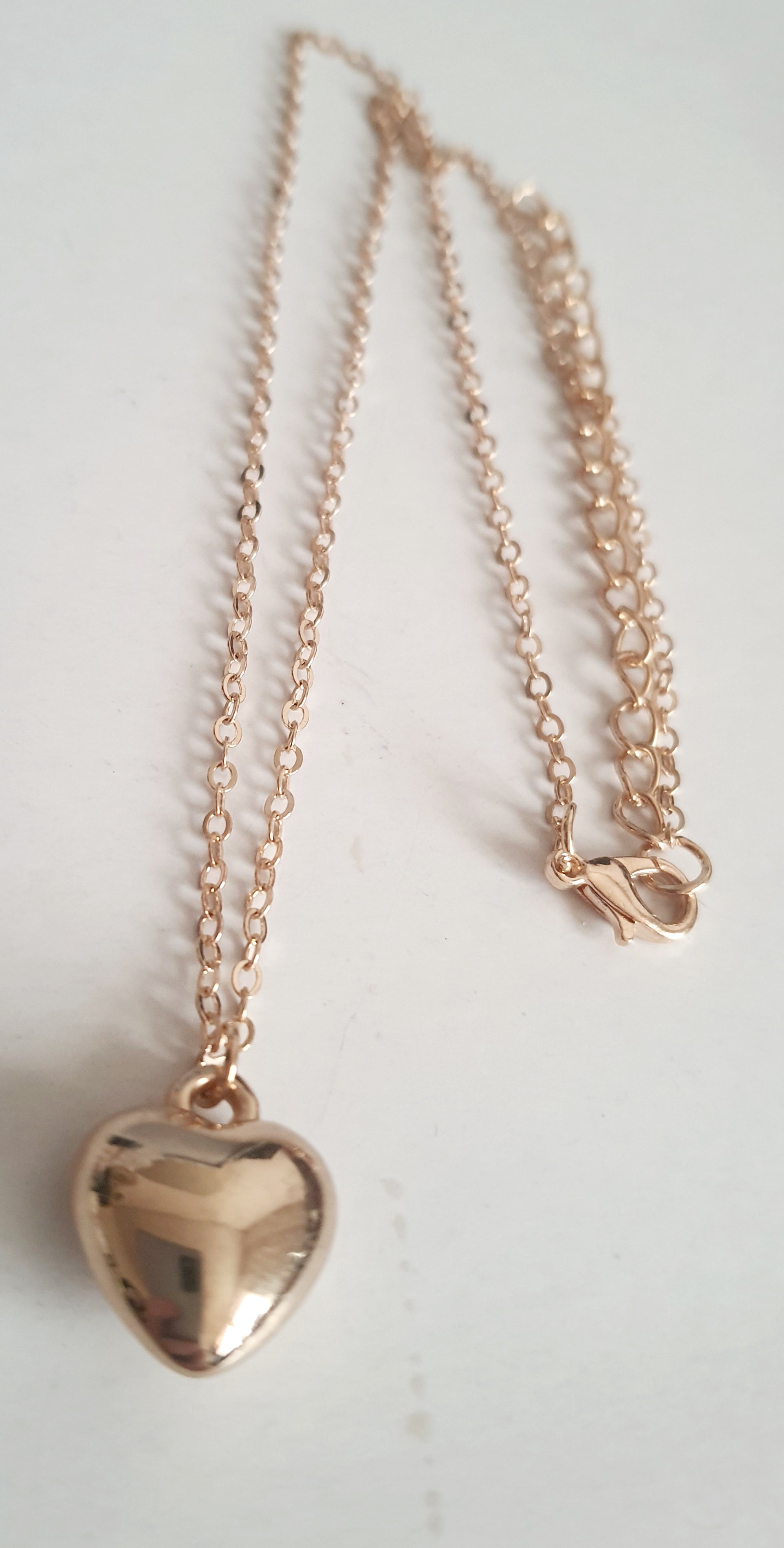 Złoty naszyjnik ze stali nierdzewnej z zawieszką w kształcie serca na jasnym tle,  długośc regulowana. prostota i elegancja. rougebizu