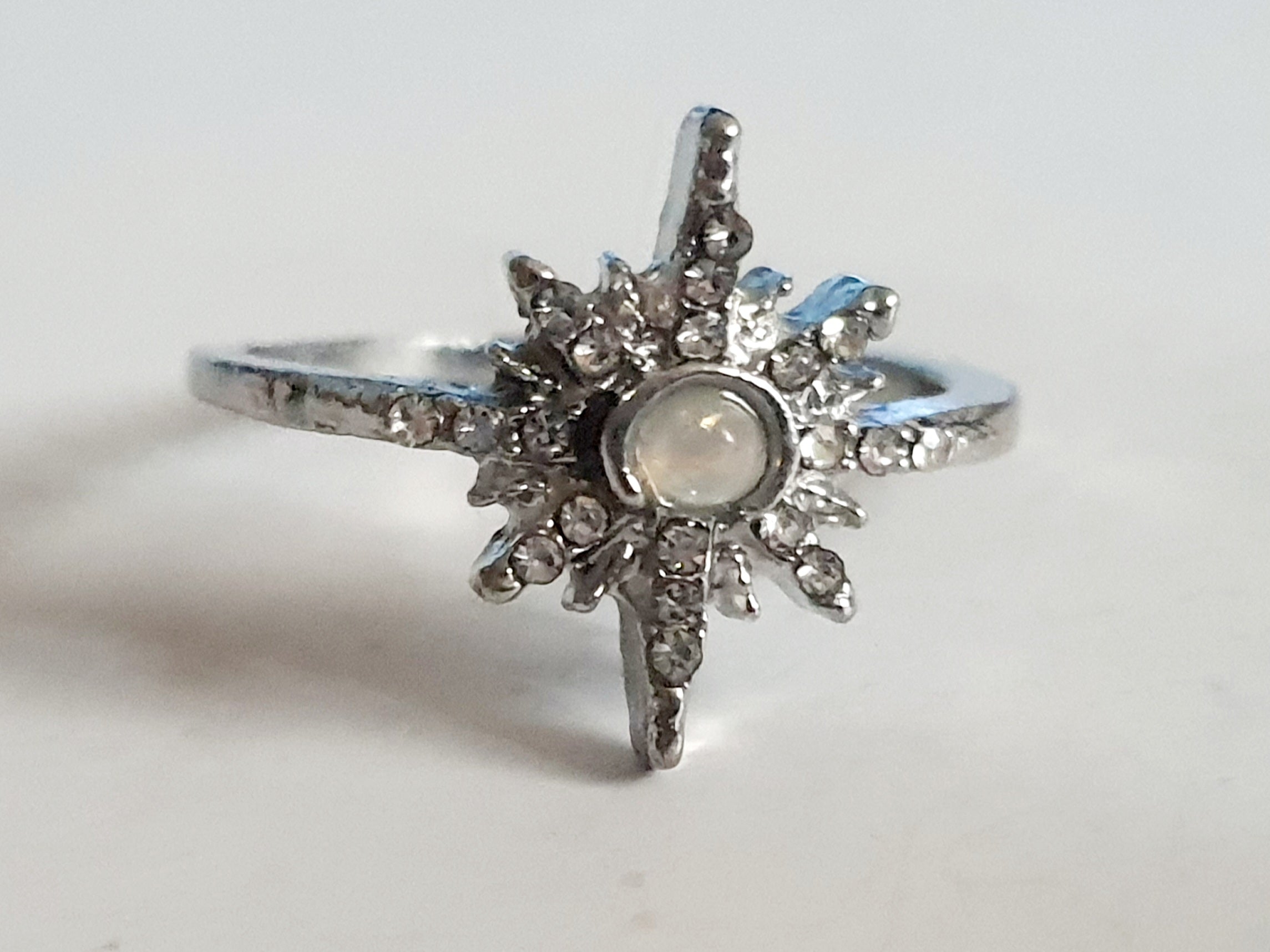 Srebrny pierścionek ze stali nierdzewnej i chirurgicznej z opalizującym kamieniem i cyrkoniami w kształcie gwiazdy, styl glamour i romantyczny, rozmiar 18 mm. Wodoodporny, hipoalergiczny, jakość premium. Rouge Bizu.