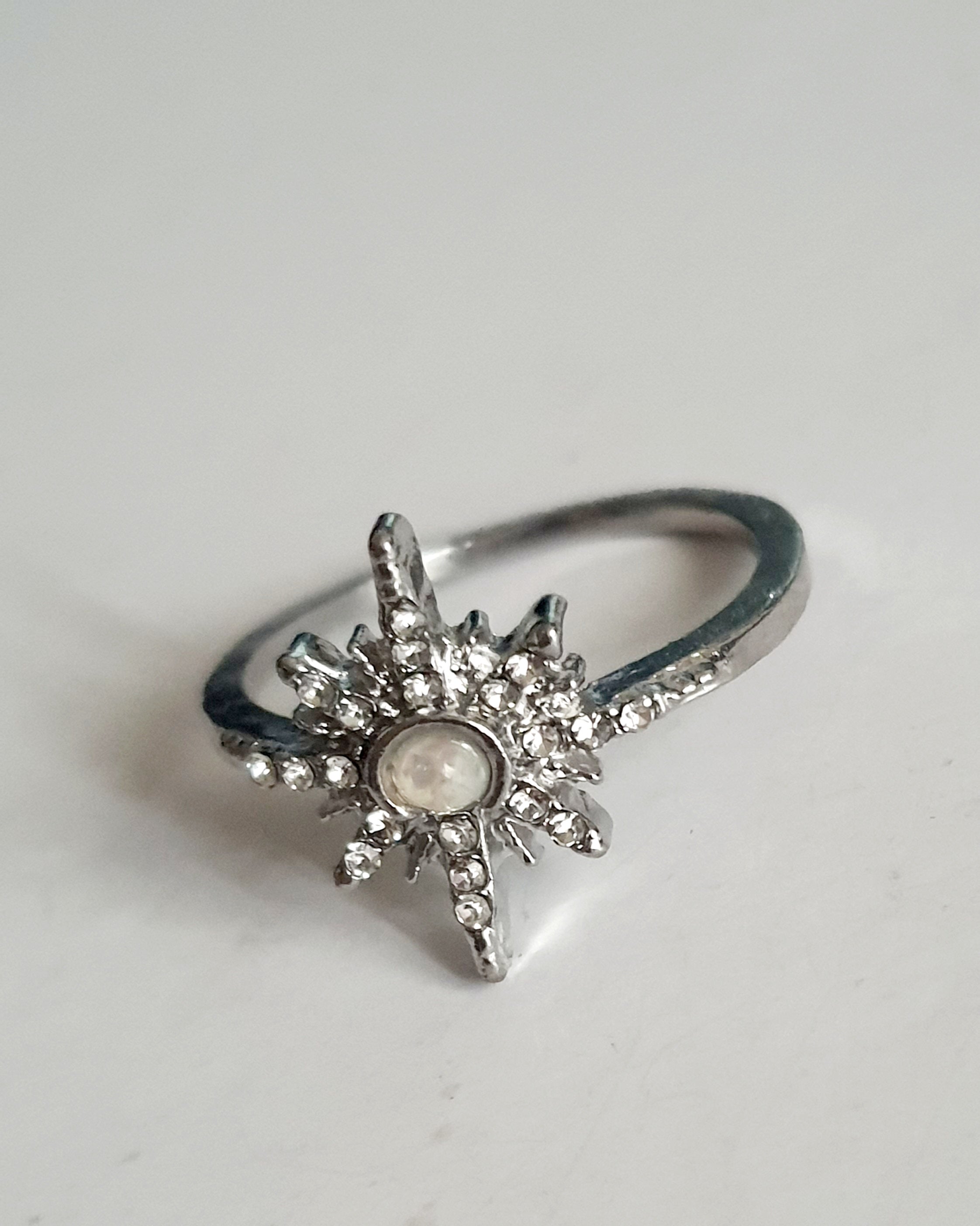 Srebrny pierścionek ze stali nierdzewnej i chirurgicznej z opalizującym kamieniem i cyrkoniami w kształcie gwiazdy, styl glamour i romantyczny, rozmiar 18 mm. Wodoodporny, hipoalergiczny, jakość premium. Rouge Bizu.