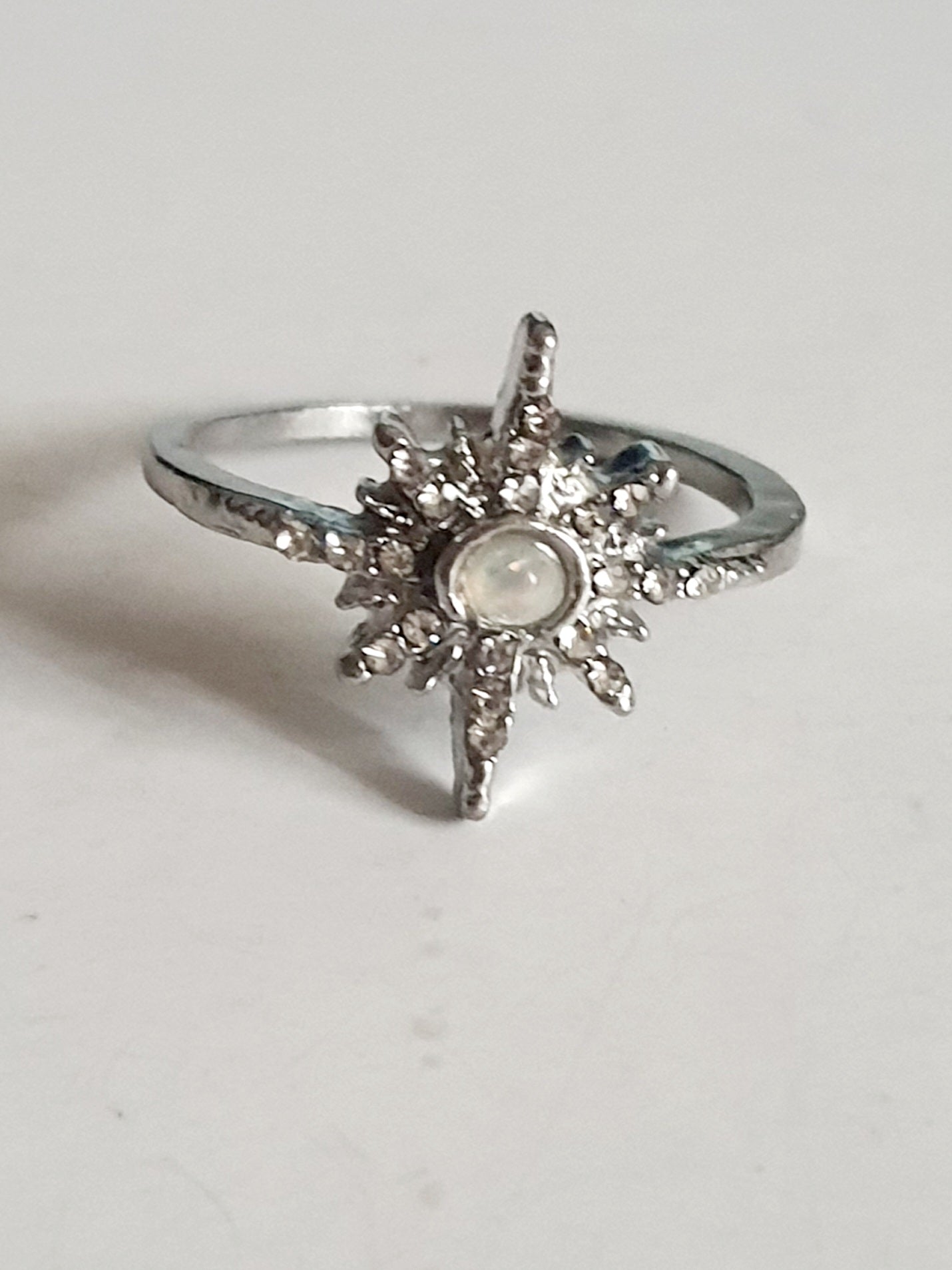 Srebrny pierścionek ze stali nierdzewnej i chirurgicznej z opalizującym kamieniem i cyrkoniami w kształcie gwiazdy, styl glamour i romantyczny, rozmiar 18 mm. Wodoodporny, hipoalergiczny, jakość premium. Rouge Bizu.