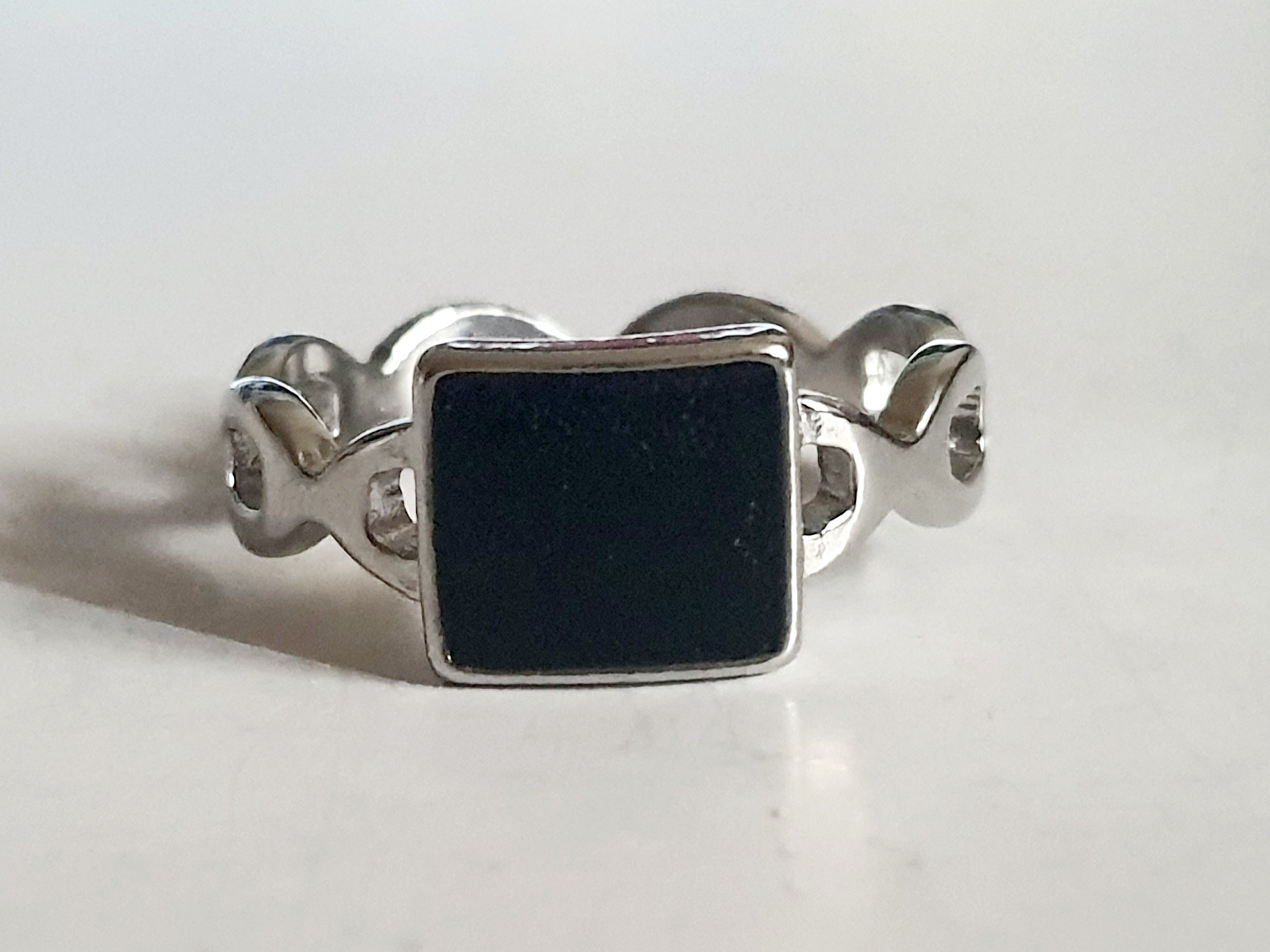 Srebrny pierścionek ze stali nierdzewnej i chirurgicznej z czarnym kwadratowym akcentem i falistą obrączką, styl geometryczny i minimalistyczny, rozmiar 20 mm. Wodoodporny, hipoalergiczny, jakość premium. Rouge Bizu.