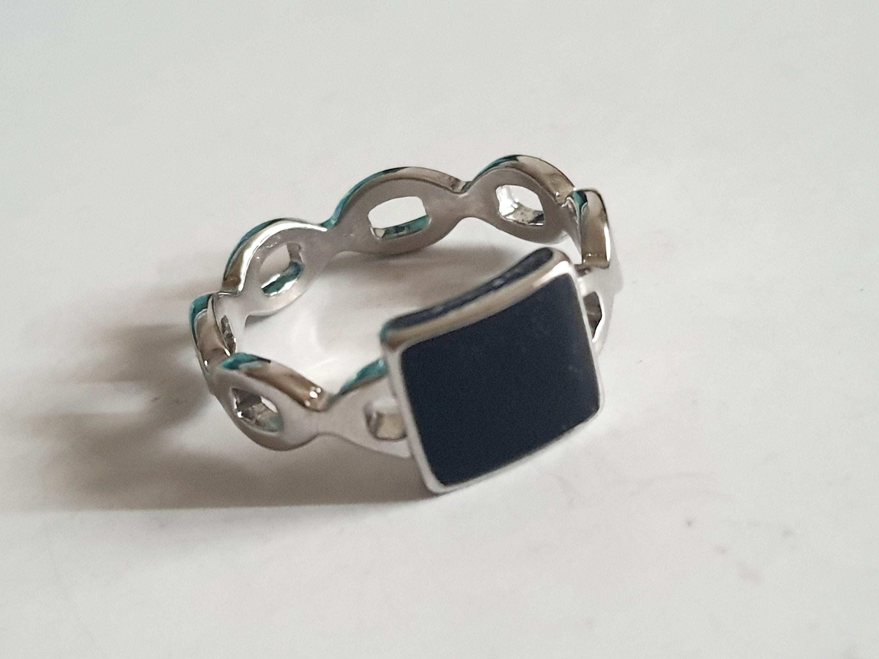 Srebrny pierścionek ze stali nierdzewnej i chirurgicznej z czarnym kwadratowym akcentem i falistą obrączką, styl geometryczny i minimalistyczny, rozmiar 20 mm. Wodoodporny, hipoalergiczny, jakość premium. Rouge Bizu.