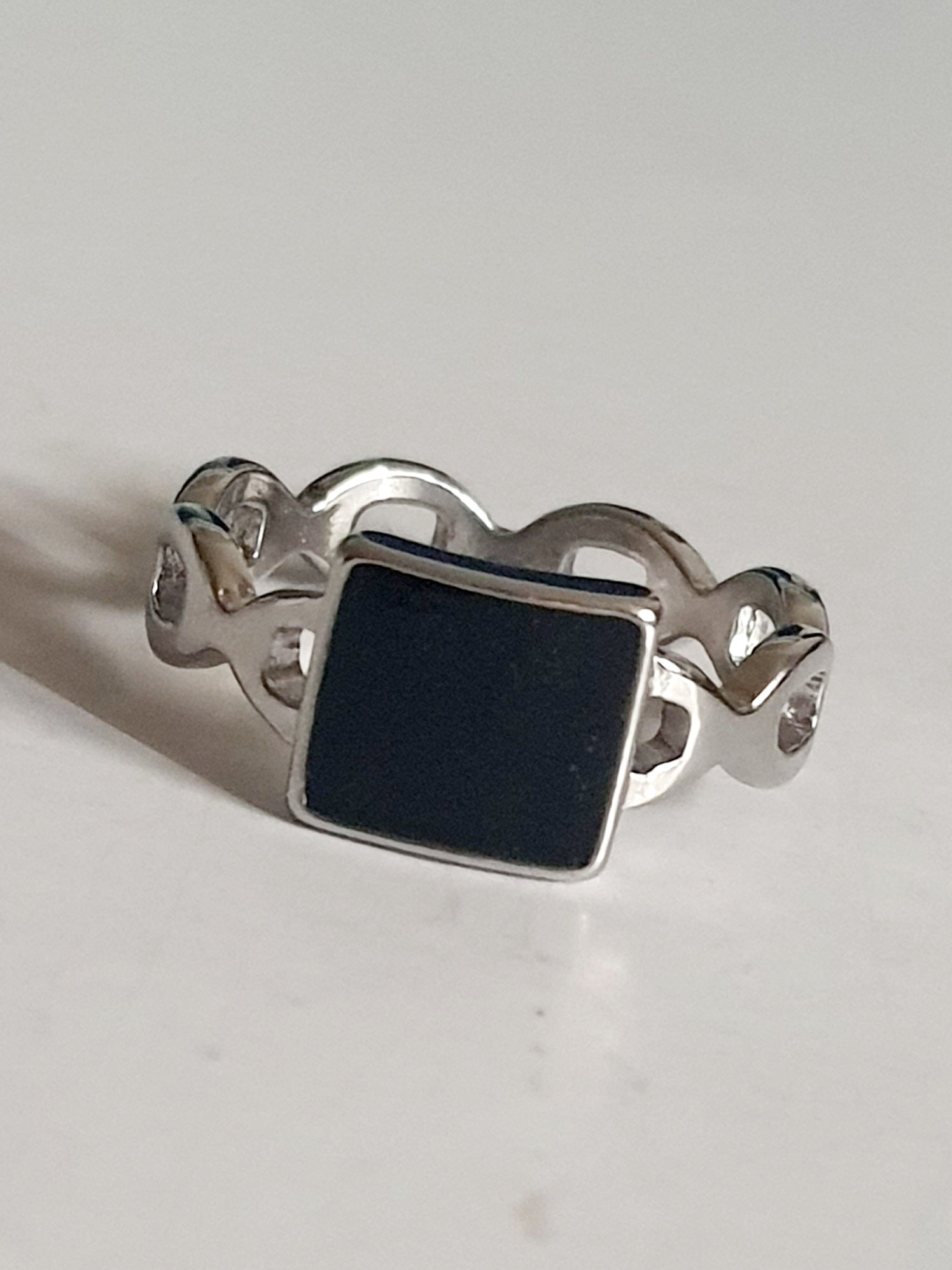 Srebrny pierścionek ze stali nierdzewnej i chirurgicznej z czarnym kwadratowym akcentem i falistą obrączką, styl geometryczny i minimalistyczny, rozmiar 20 mm. Wodoodporny, hipoalergiczny, jakość premium. Rouge Bizu.